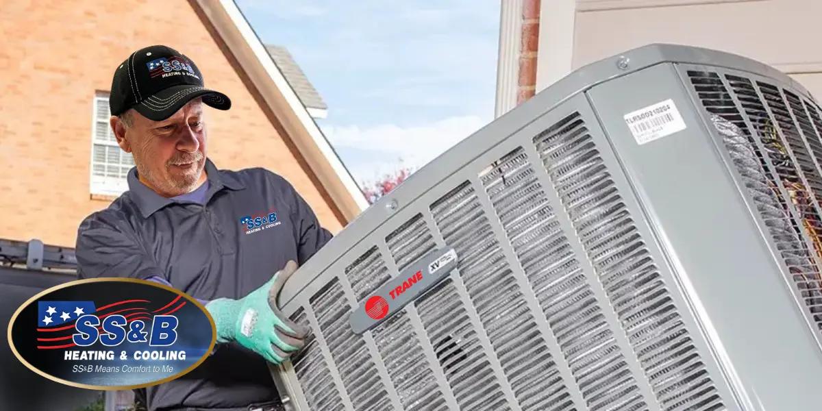 SS&B Heating & Cooling technician installing a new Trane air conditioning unit outside a residential home. The technician is wearing SS&B branded gear, ensuring professional HVAC service in Springfield, MO.
