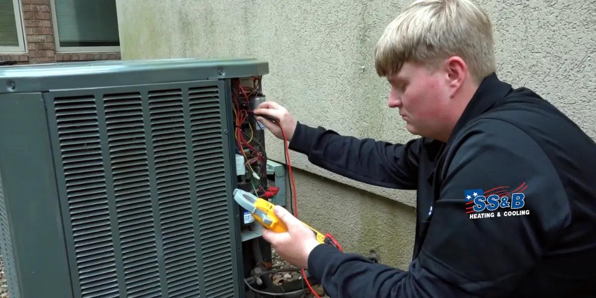 SS&B Heating & Cooling technician diligently servicing an air conditioning unit to ensure optimal performance and efficiency for summer comfort.