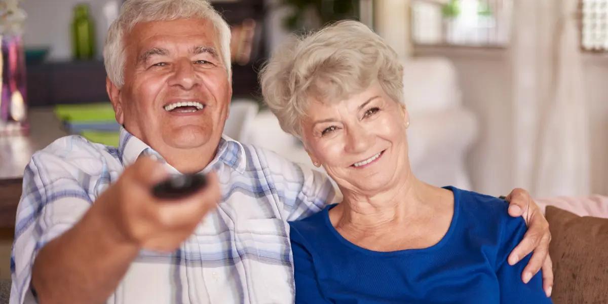Seniors smiling comfortably in their well-ventilated, energy-efficient home, highlighting the importance of proper HVAC maintenance and optimization for elder living.