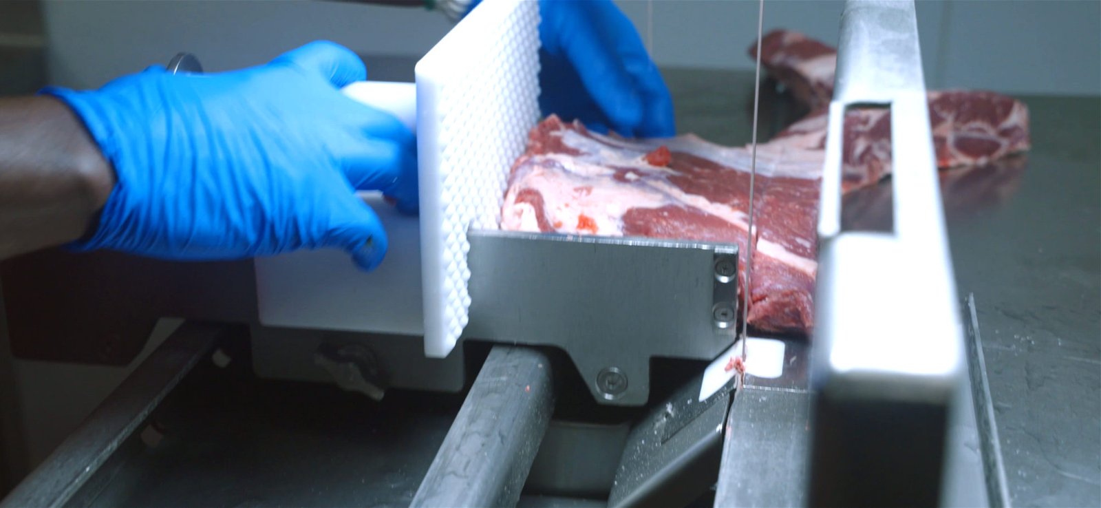 Sliding table with pusher guiding meat through the blade