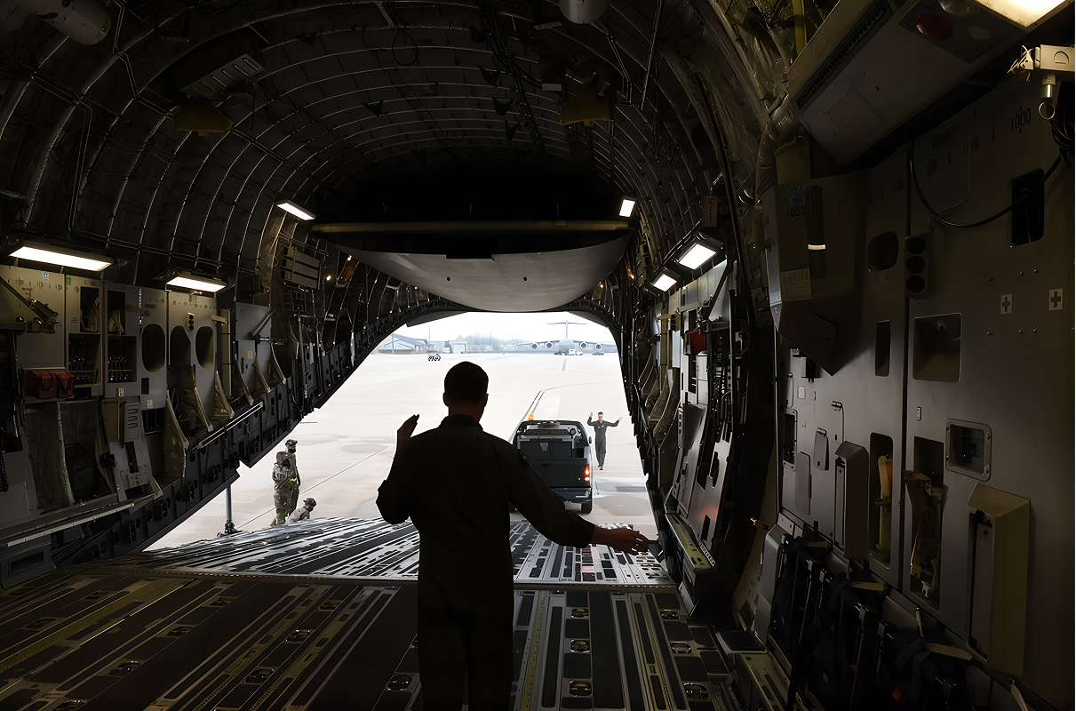 An airman directing a vehicle onto a cargo aircraft