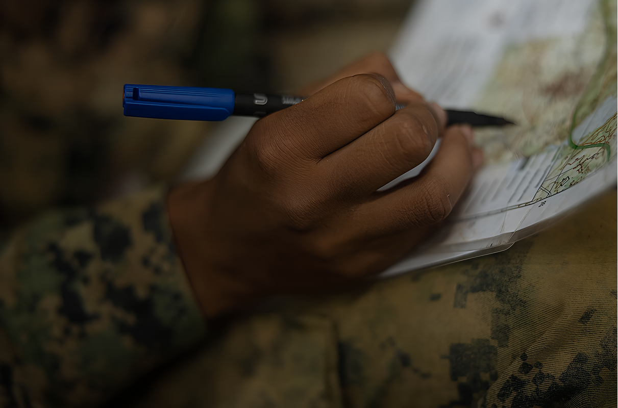 A service member marking a paper map