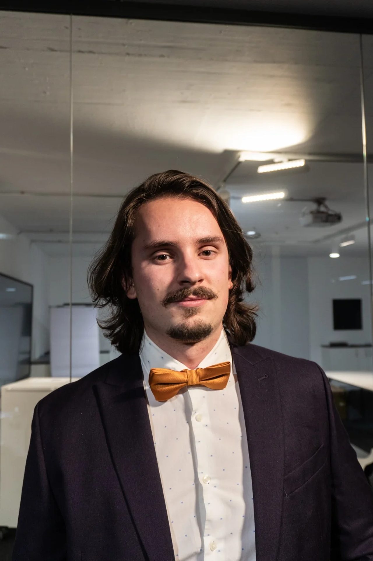 Kevin Otto Lais im Anzug mit goldener Fliege in einem Büro
