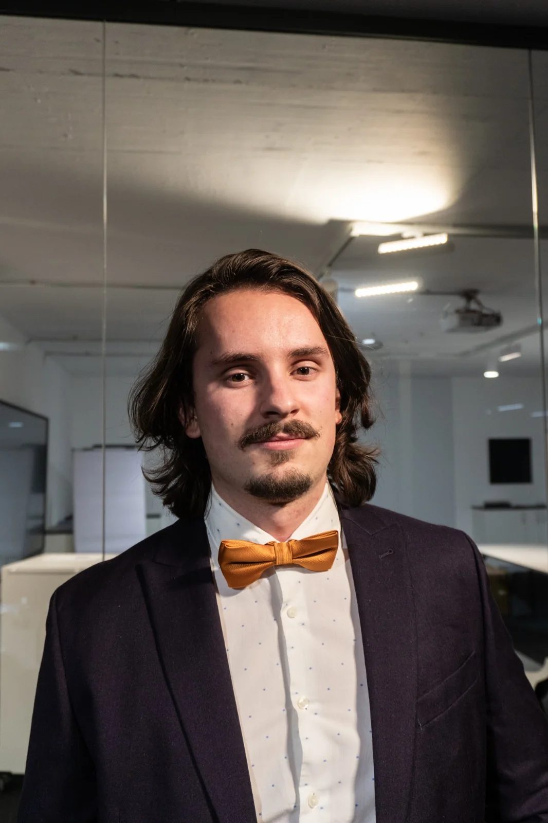 Kevin Otto Lais im Anzug mit goldener Fliege in einem Büro
