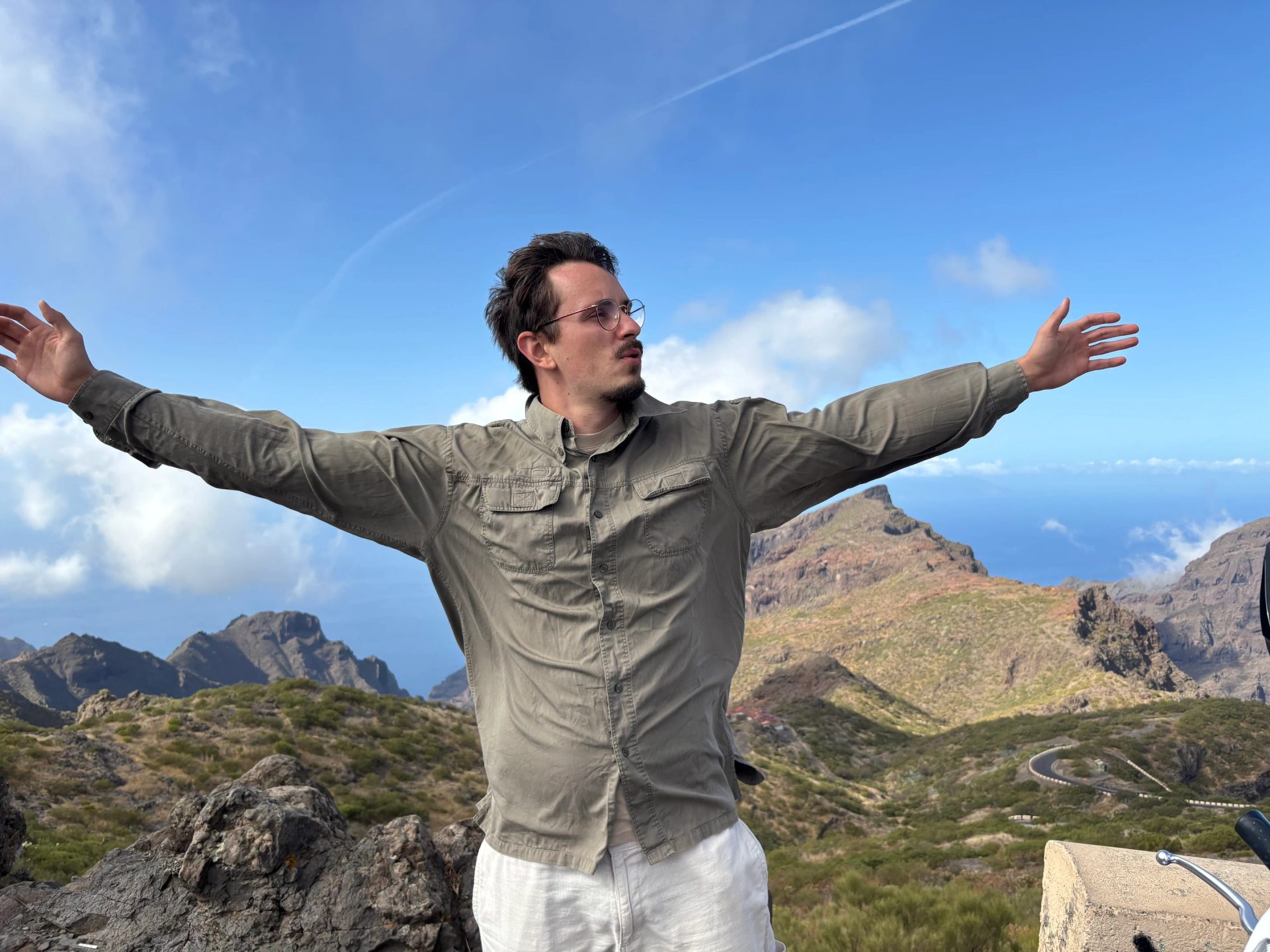 Kevin mit ausgebreiteten Armen vor einer felsigen Berglandschaft