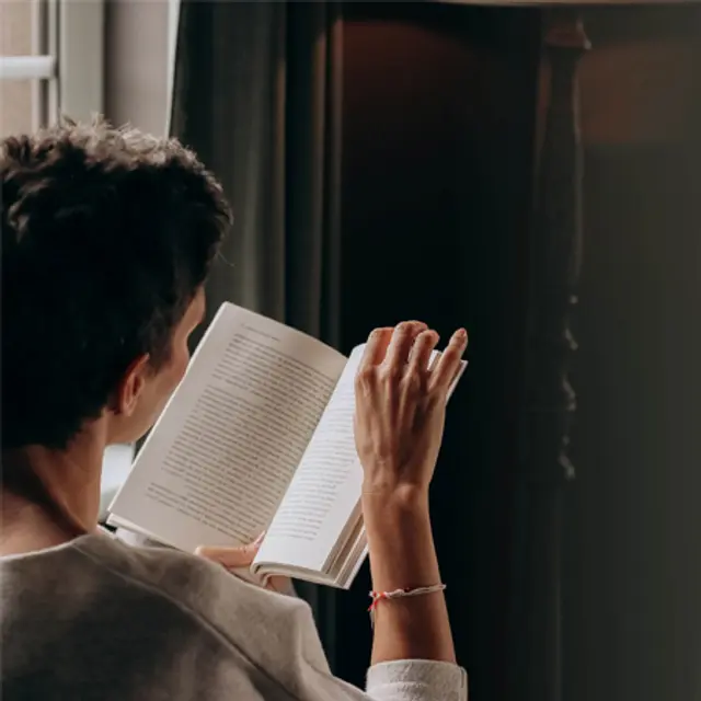 Dame bakfra som sitter og leser bok