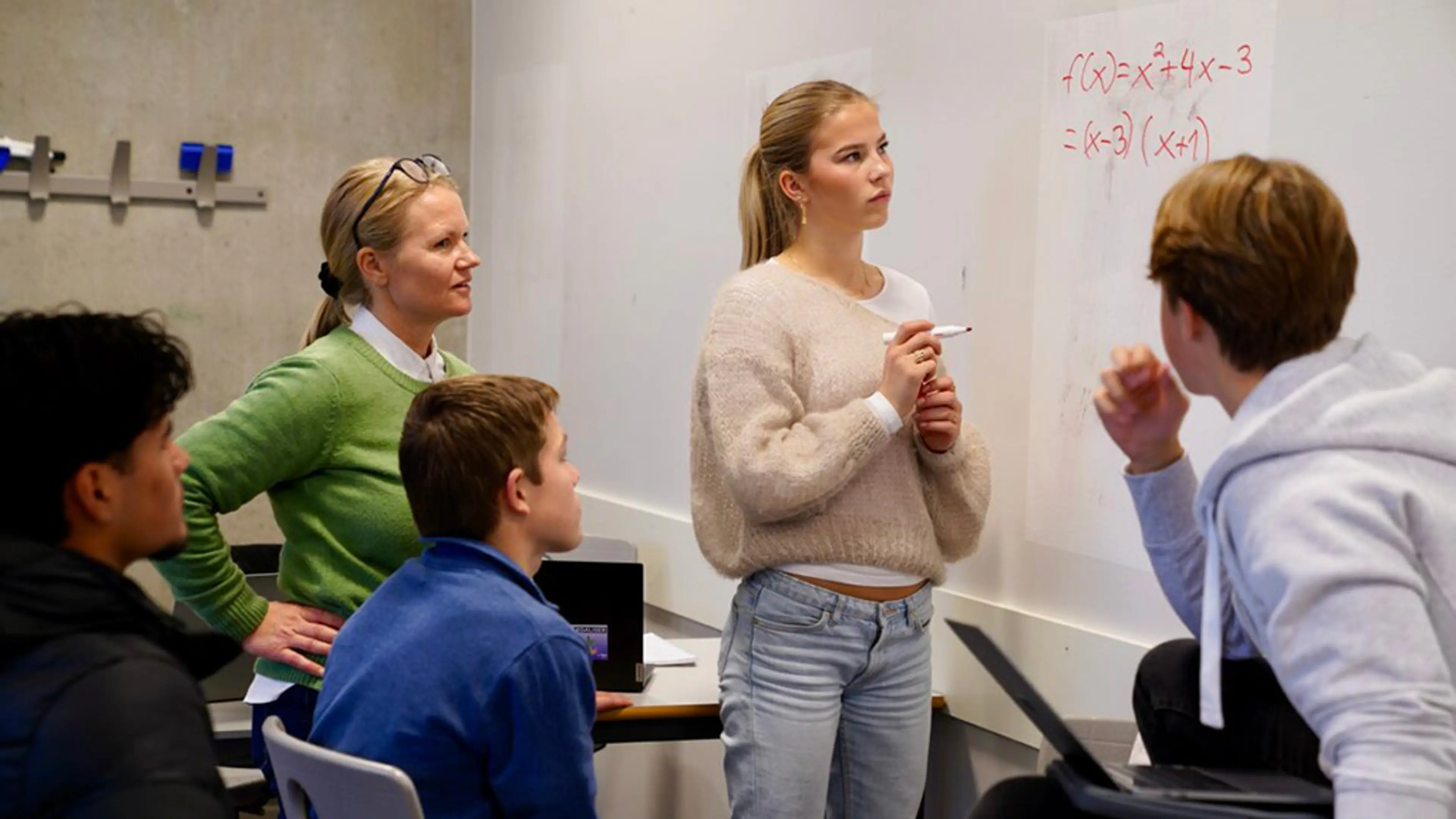 En gruppe ungdommer som ser på en tavle 