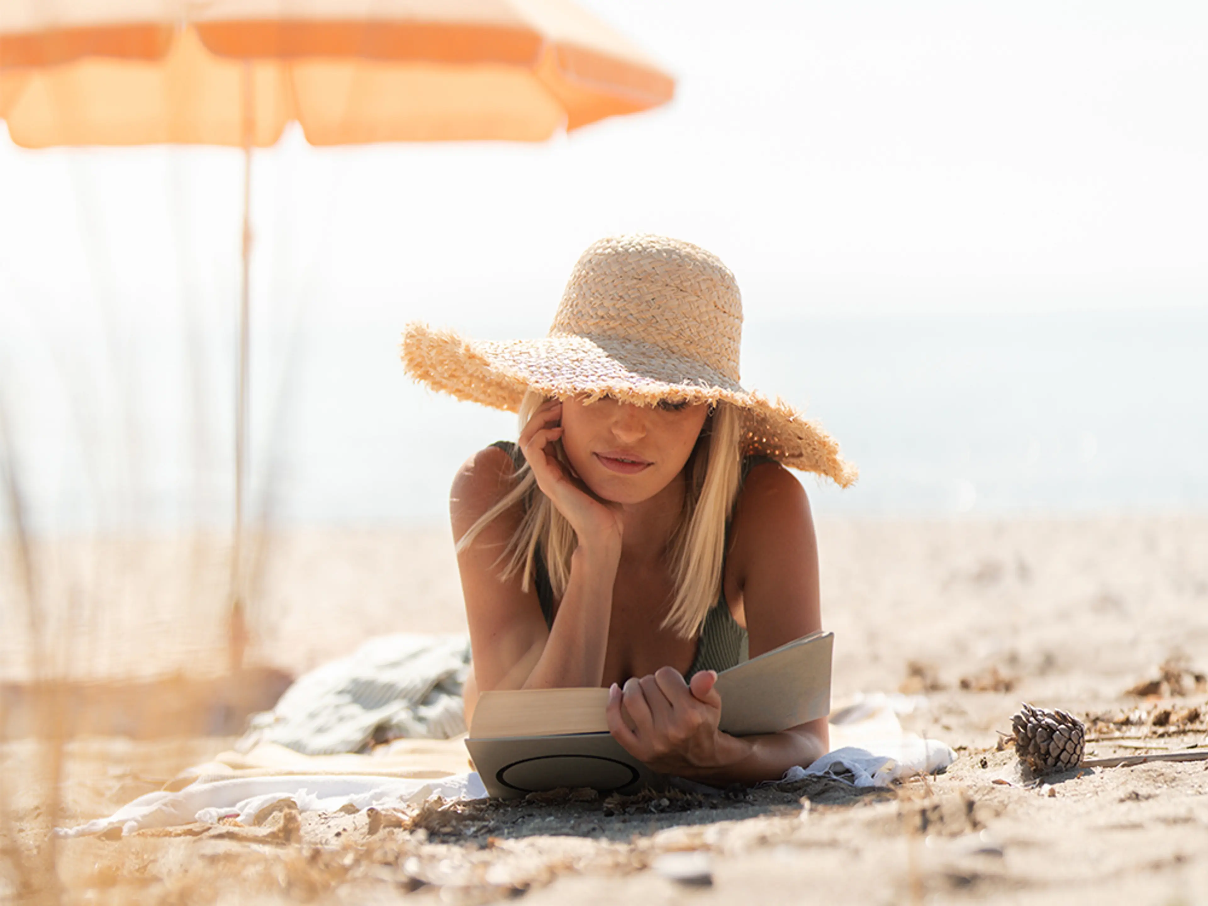 Dame på en strand som leser bok