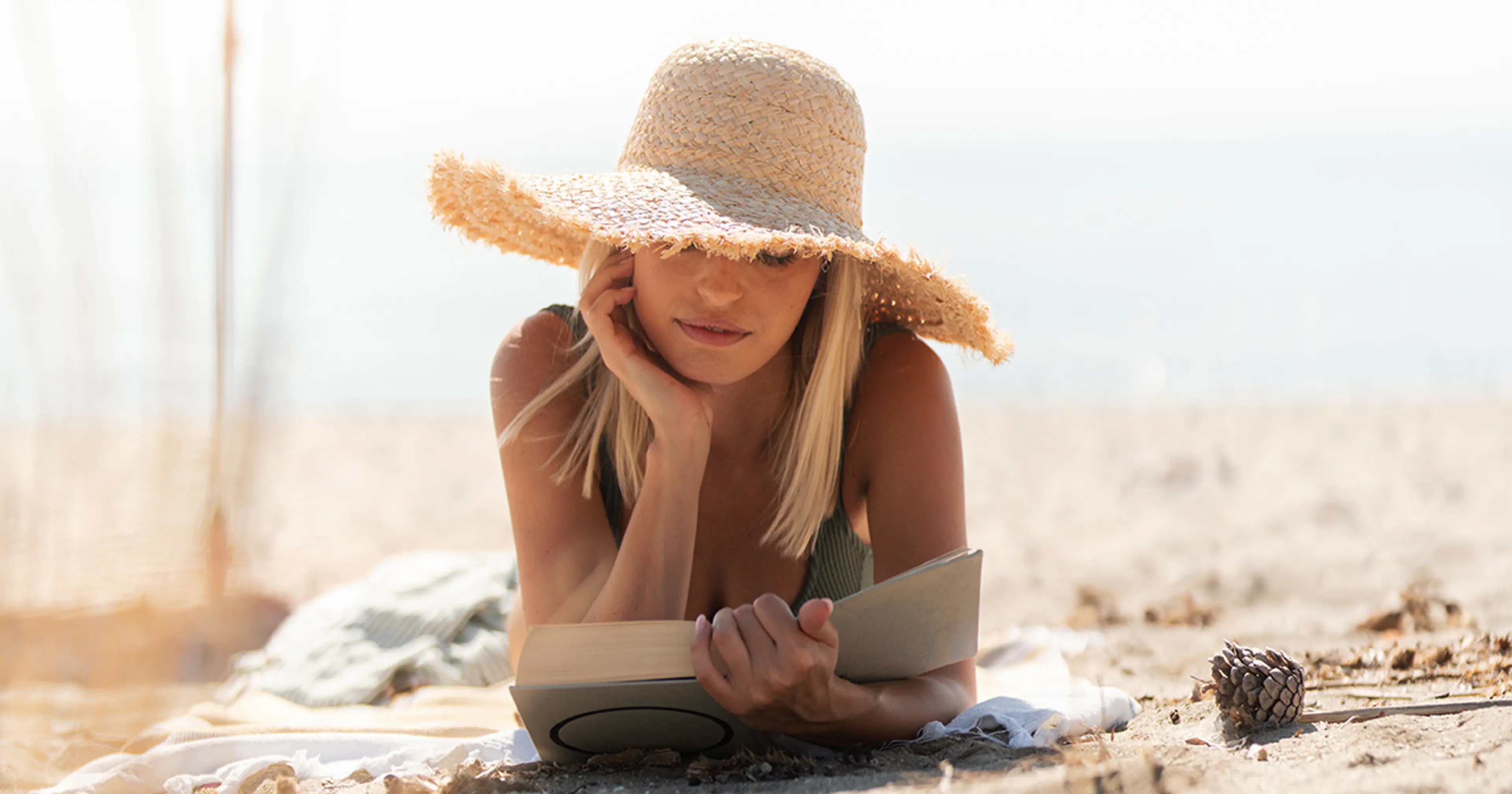 Dame på en strand som leser bok
