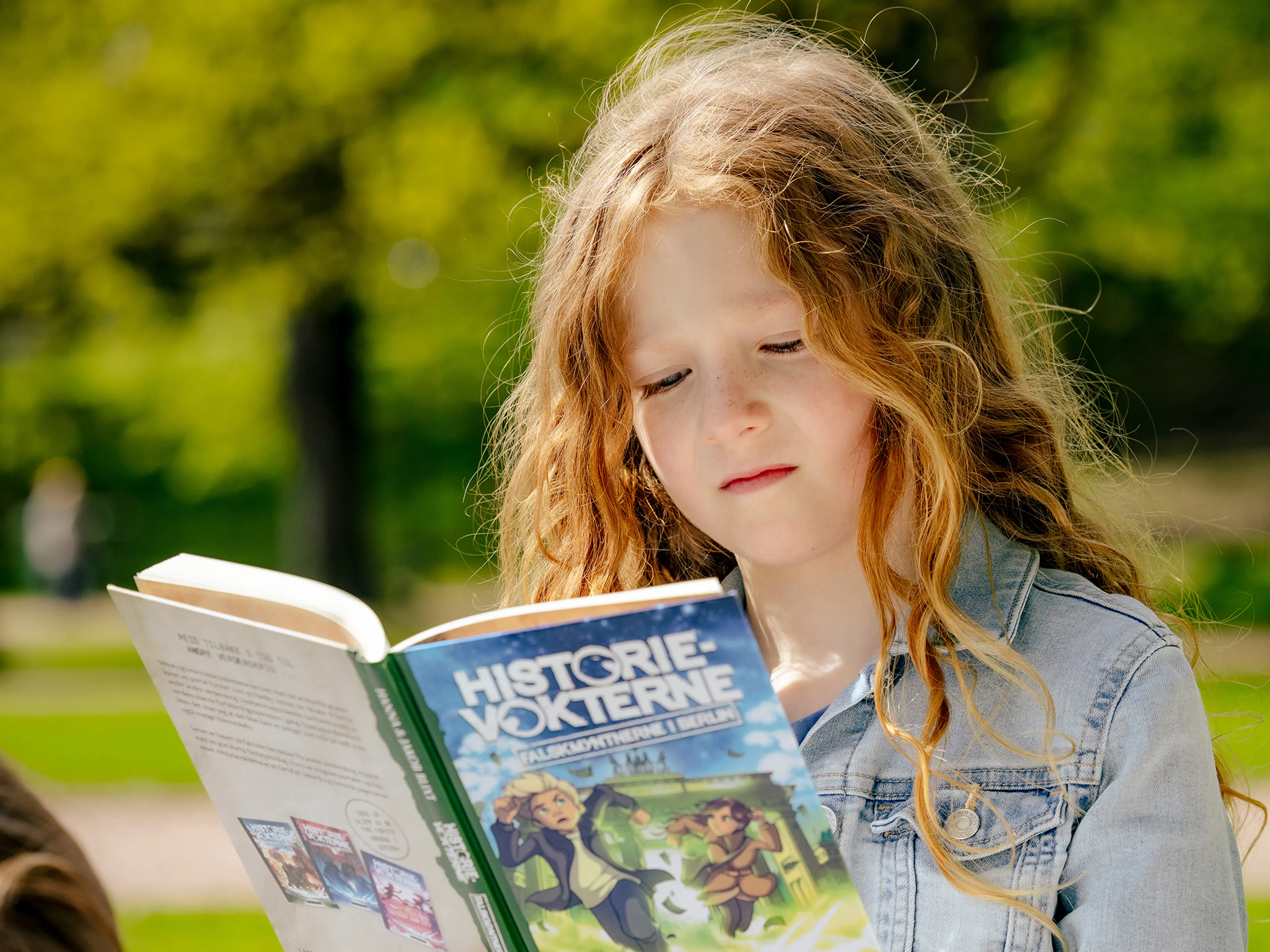 skolejente som leser historievokterne i parken