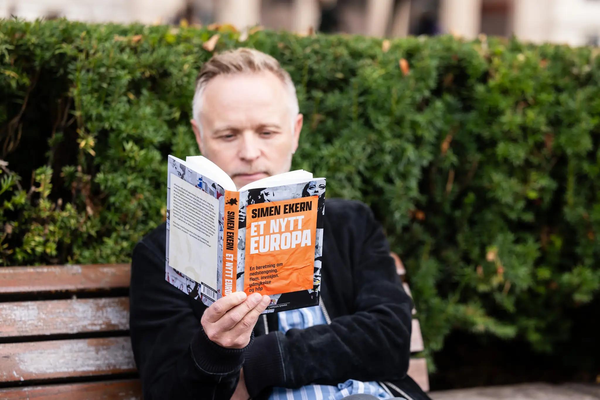 En mann leser Et nytt Europa på en benk