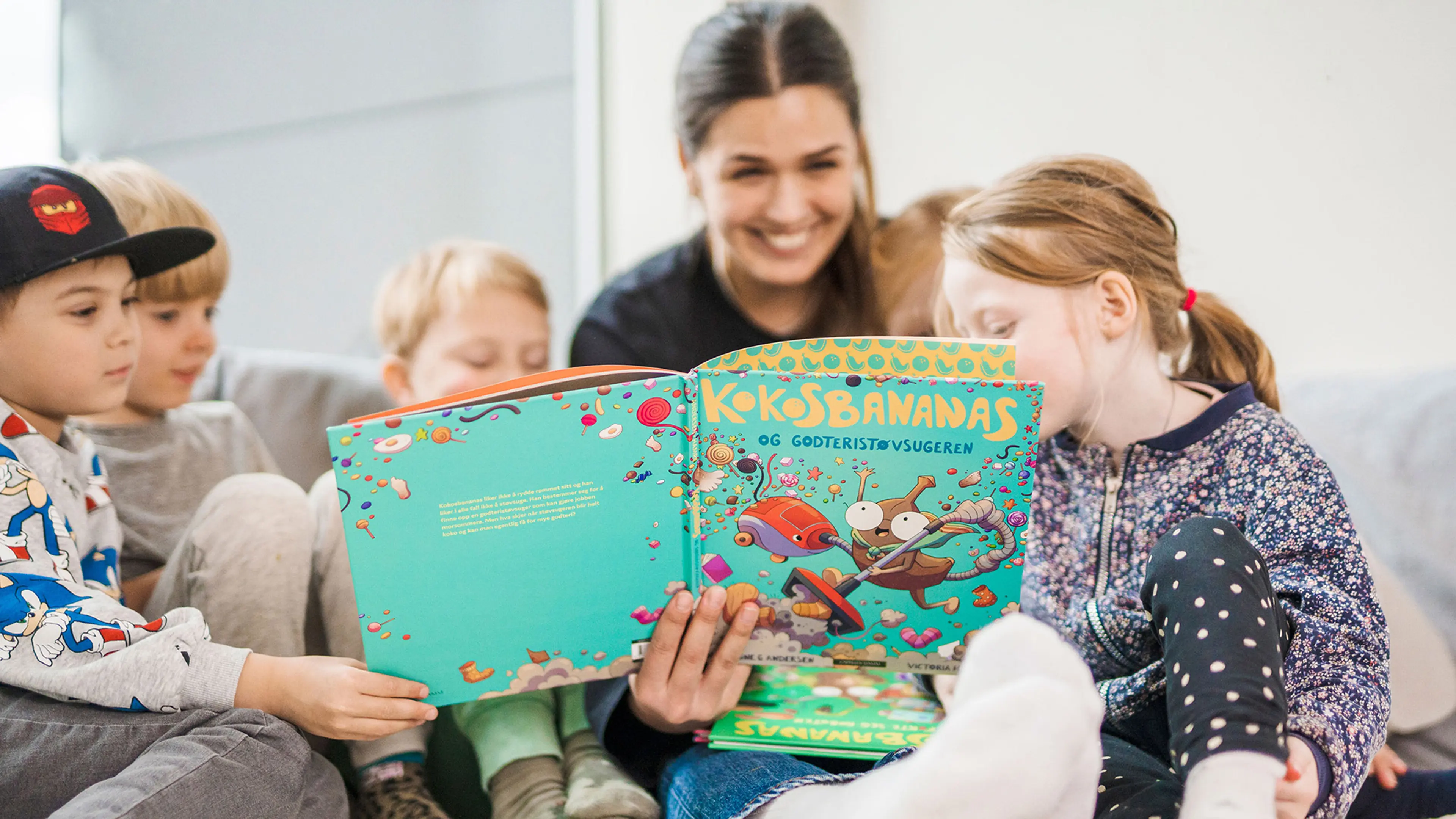 En kvinne leser Kokosbananas for en gruppe på fem barn