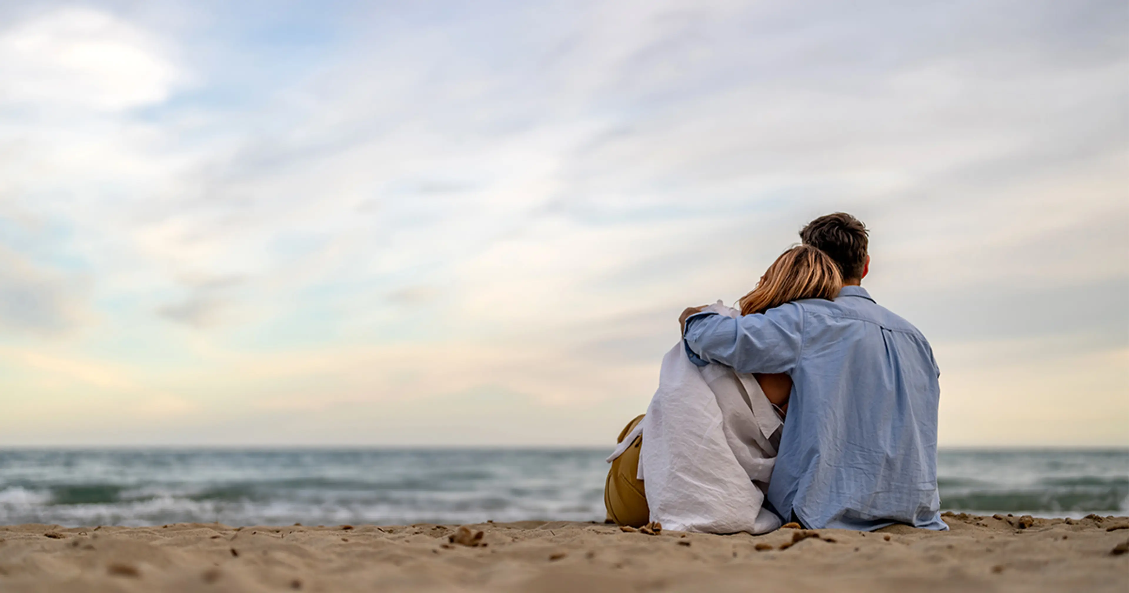 Par som holder rundt hverandre på en strand