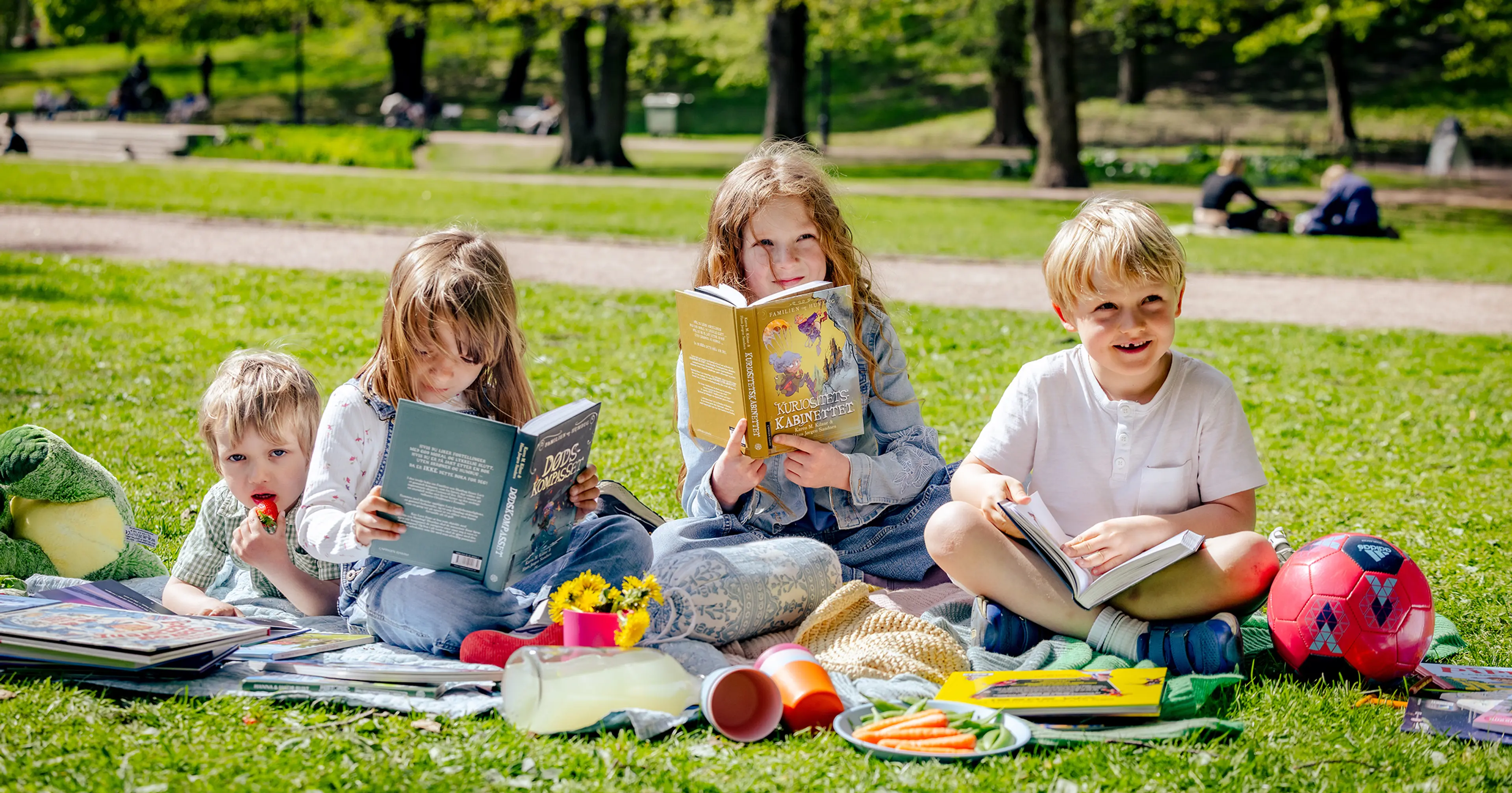 Skolebarn som leser bøker i en park en sommerdag.