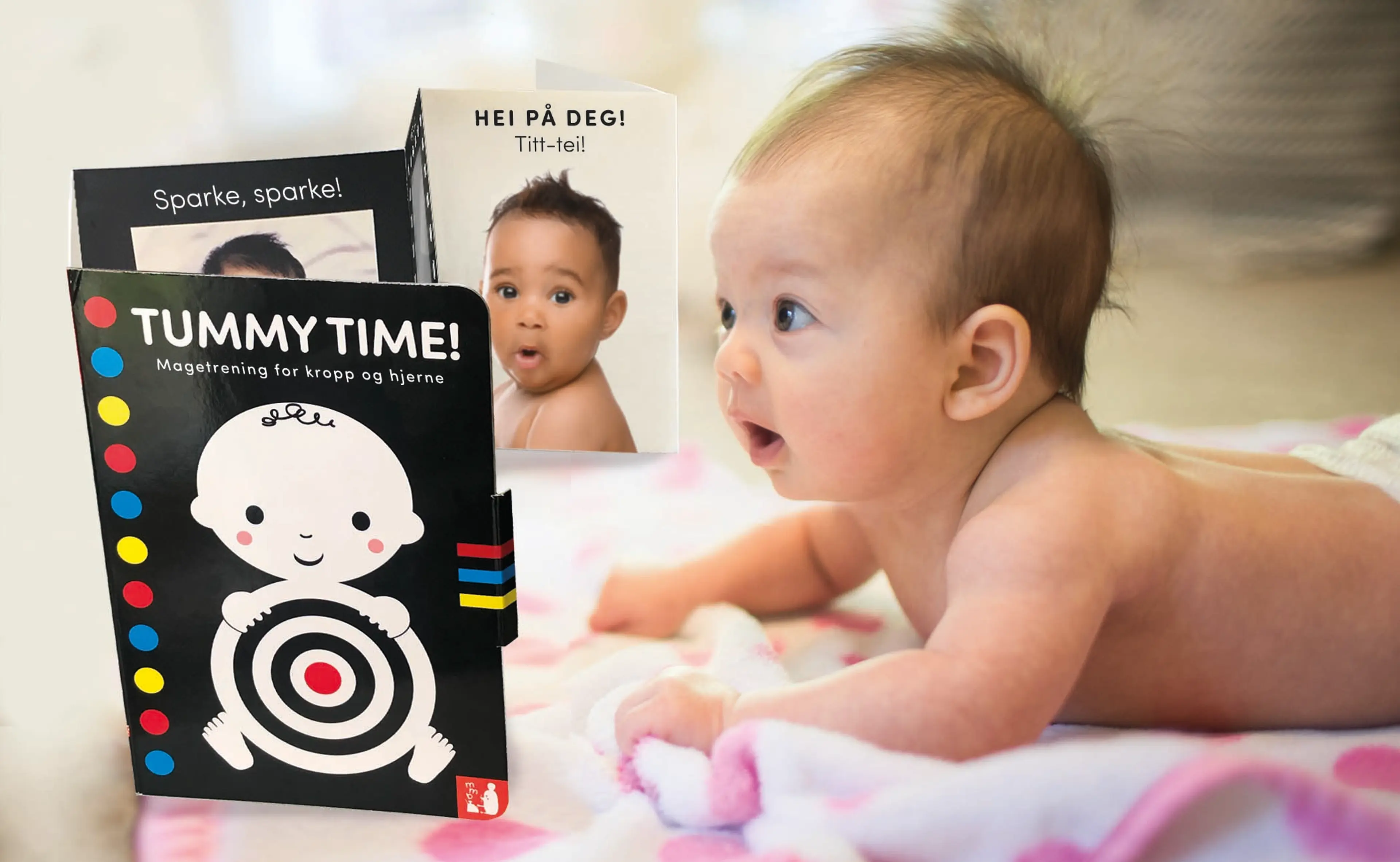 Baby ligger på magen, ser på boken Tummy Time