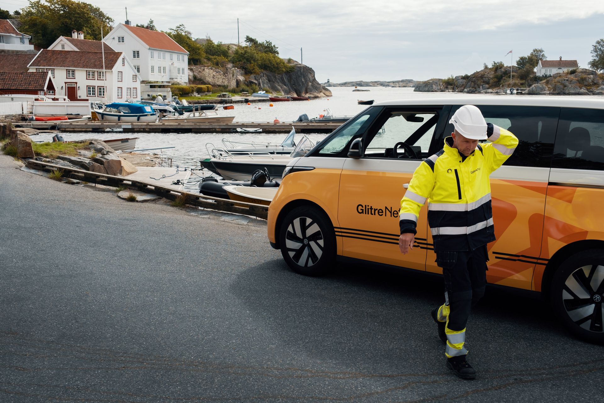 Glitre Nett bil og montør i omgivelser med vei, sjø og hus