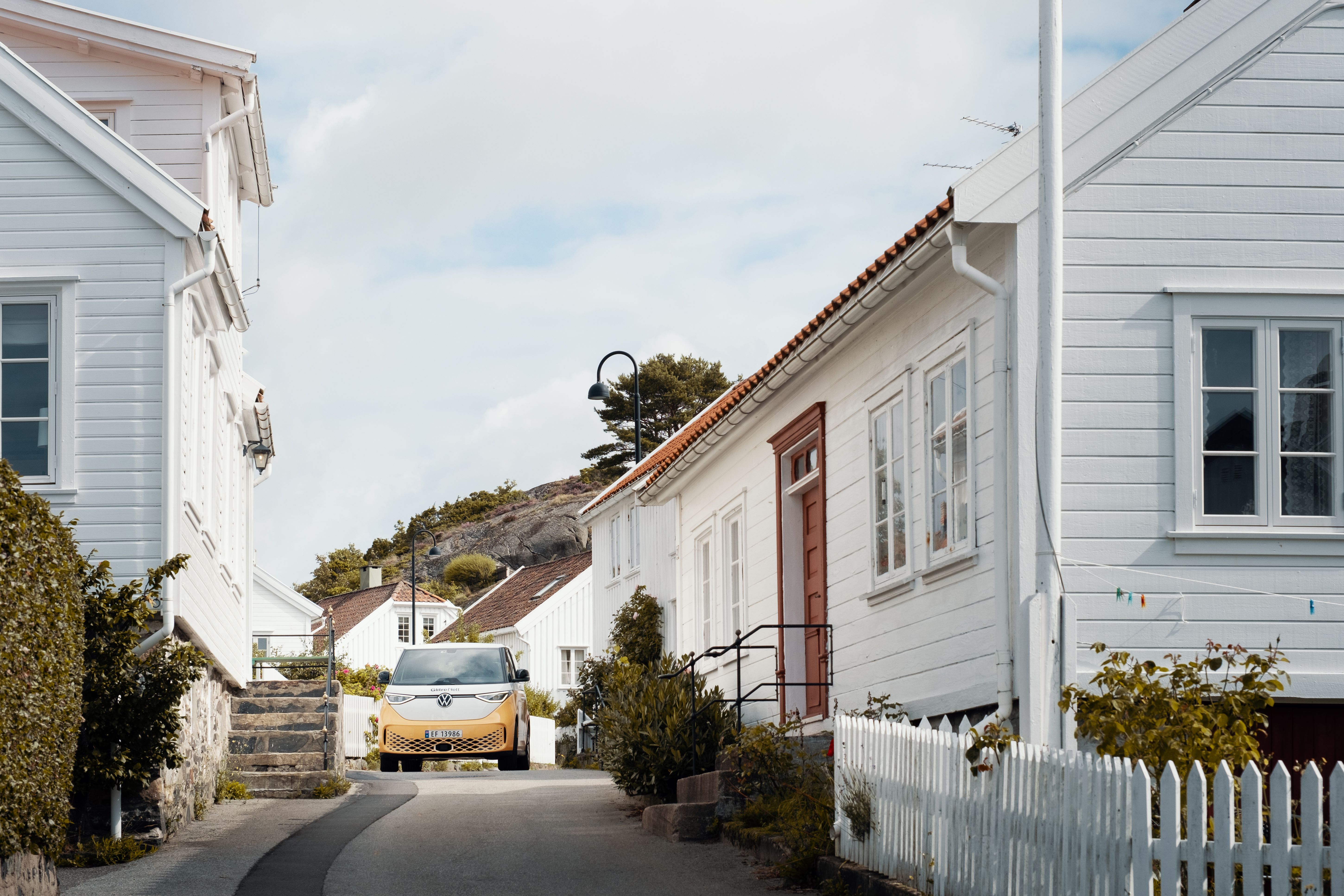 Glitre Nett bil i en gate omgitt av hvite Sørlandshus