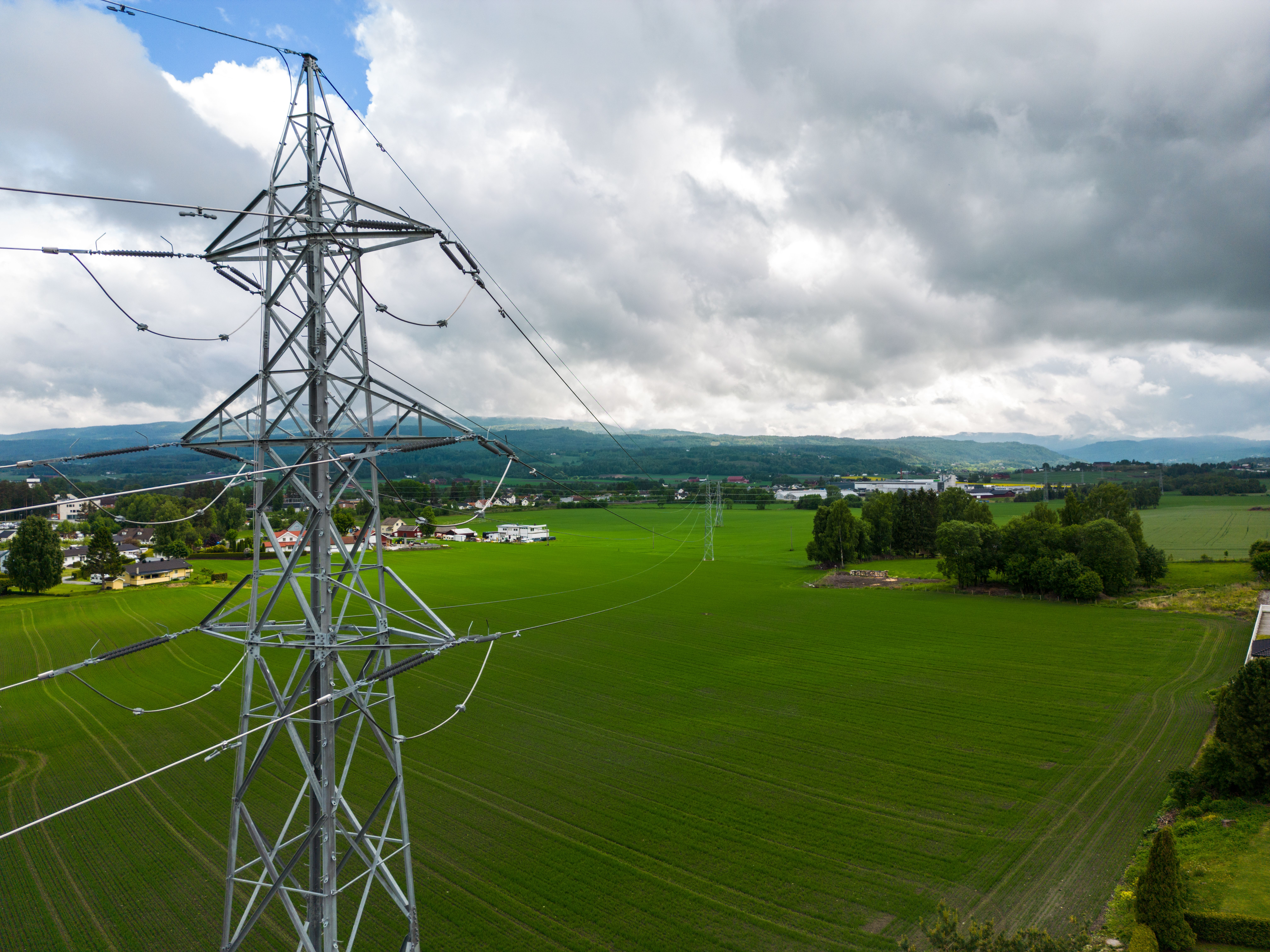 En mast og utsikt over grønne jorder med mørke skyer på himmelen