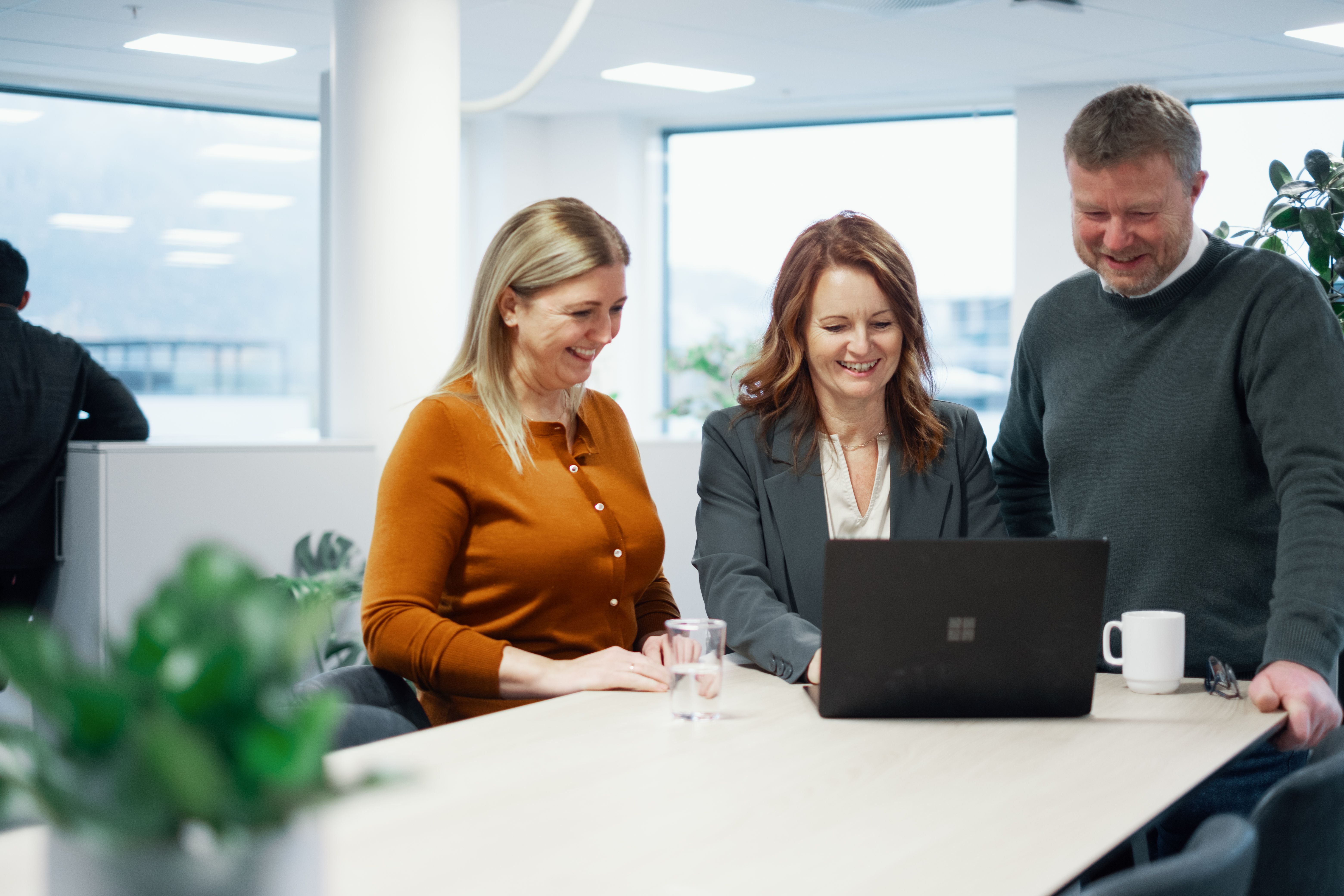 Tre medarbeidere på kontor som jobber på felles pc