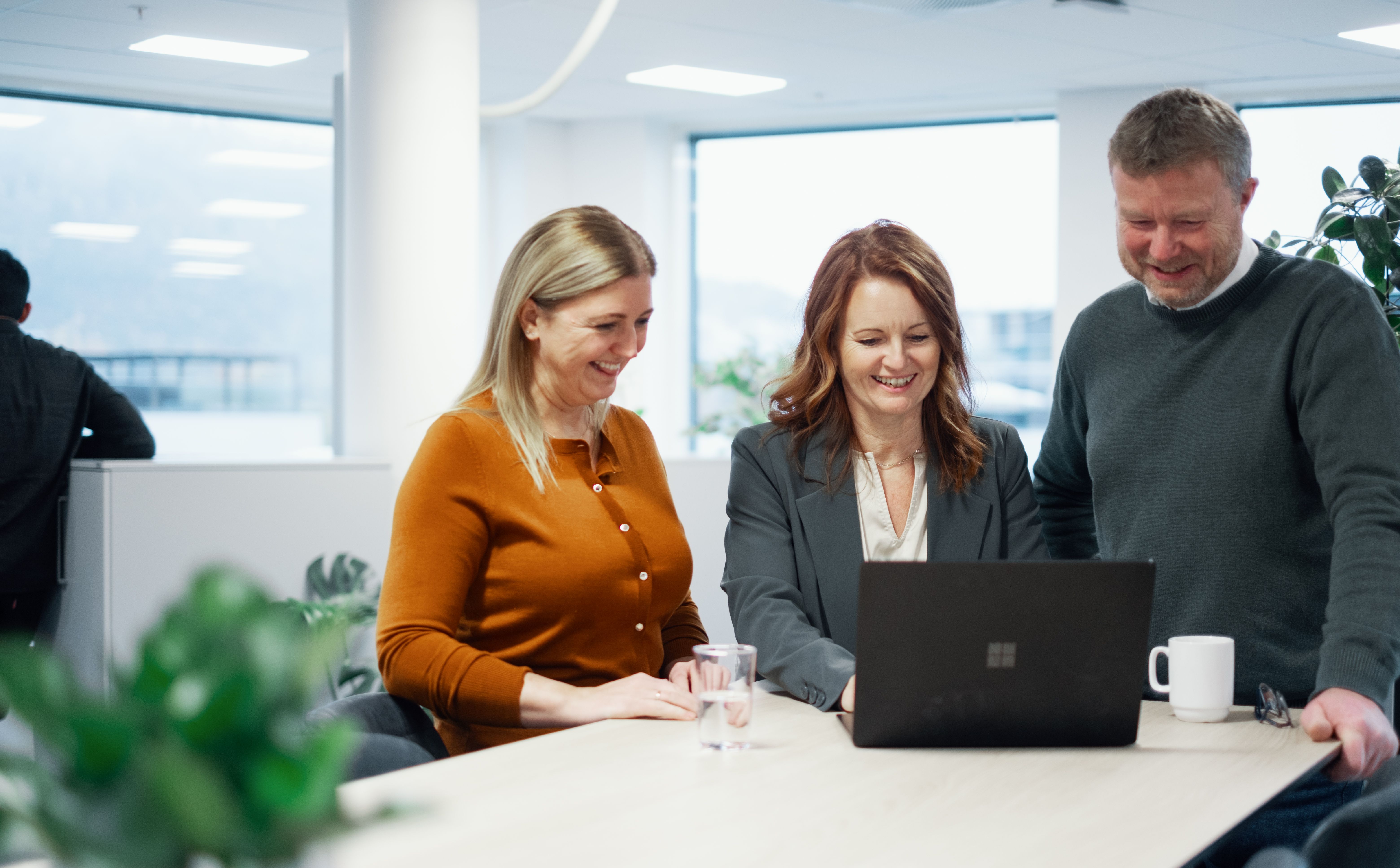 Bilde av tre ansatte som står ved en PC