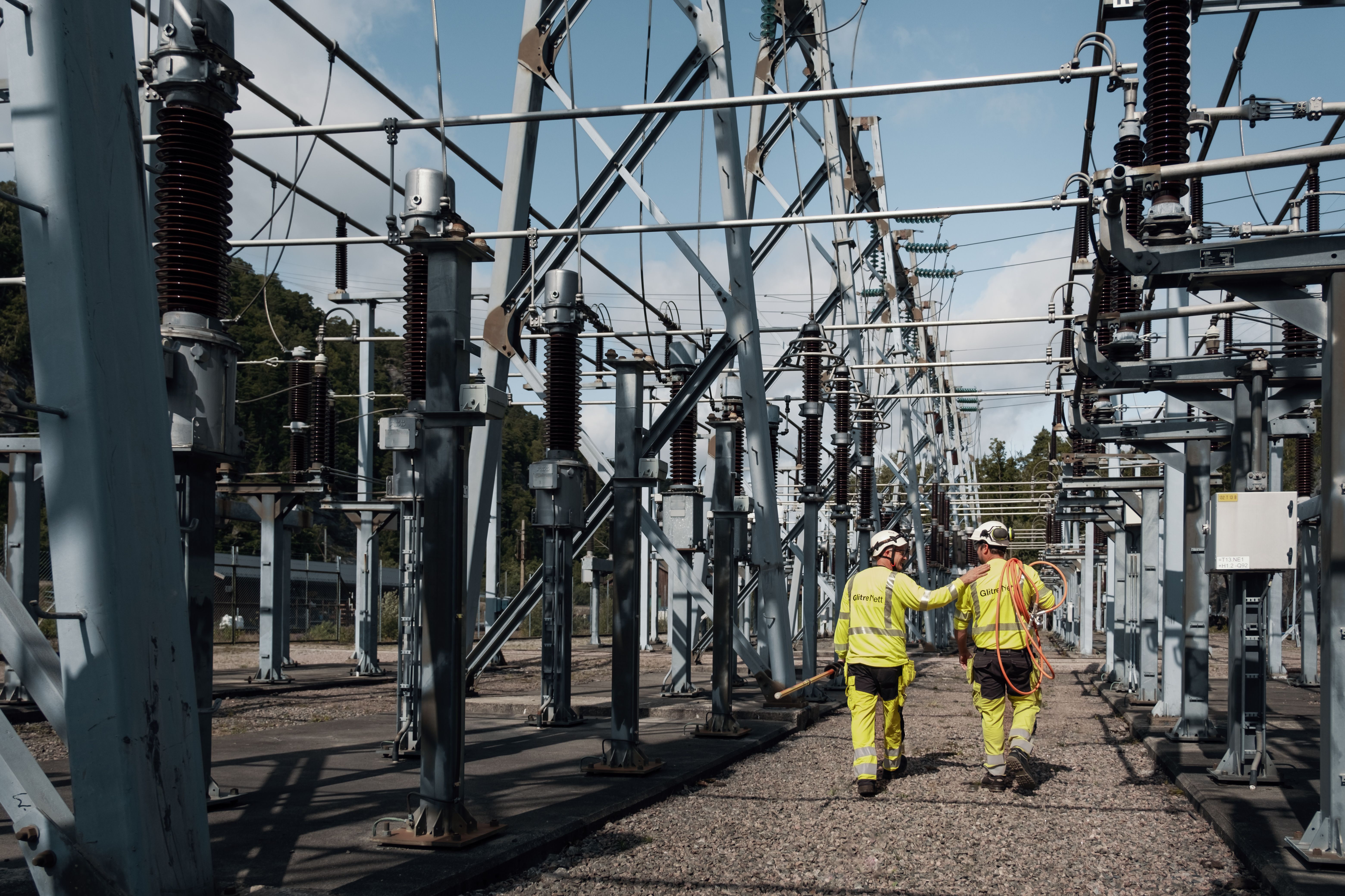 To montører som går med ryggen til inne på et nettanlegg