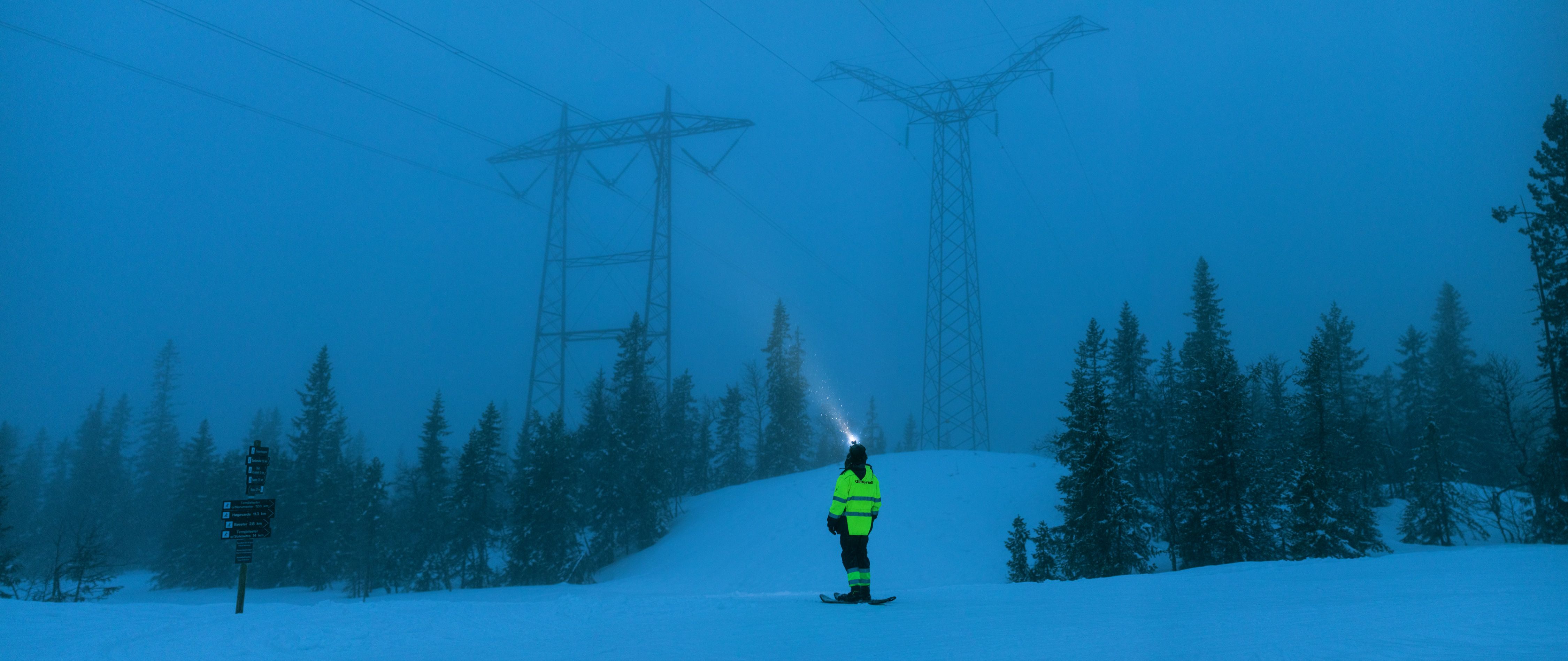 Montør i mørket, strømmaster i bakgrunnen