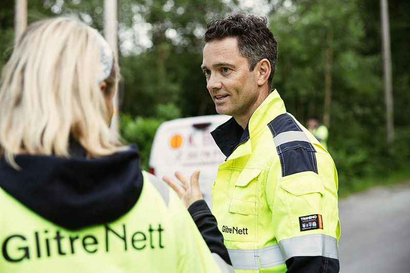 Mann i arbeidstøy som snakker med dame med arbeidstøy