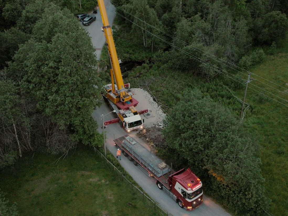 lastebil og kranbil i skogen, sett fra luften