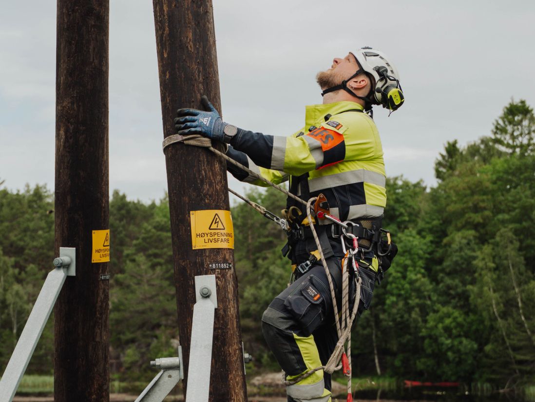 Energimontør som klatrer i strømmmast