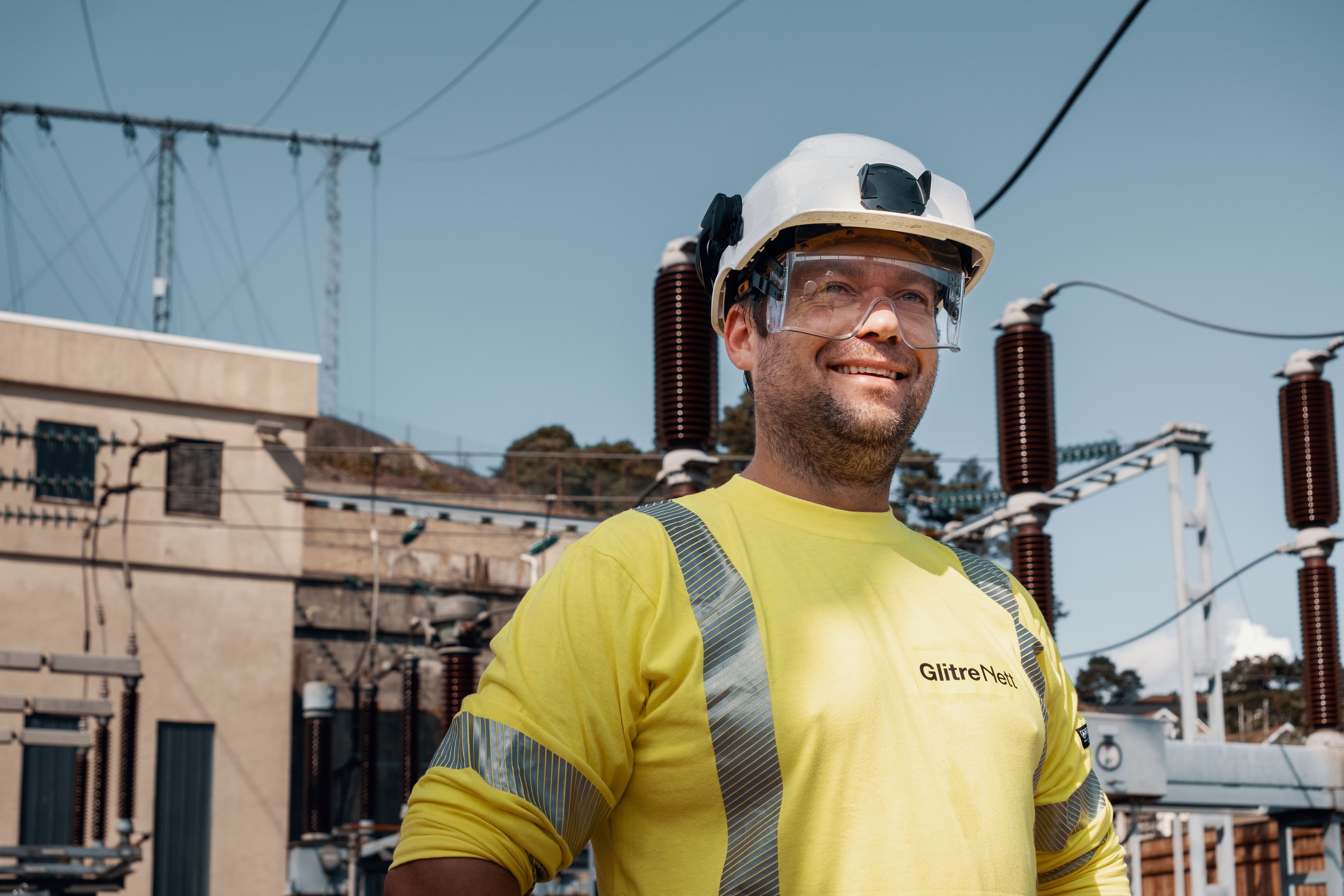Montør smiler med hjelm og briller