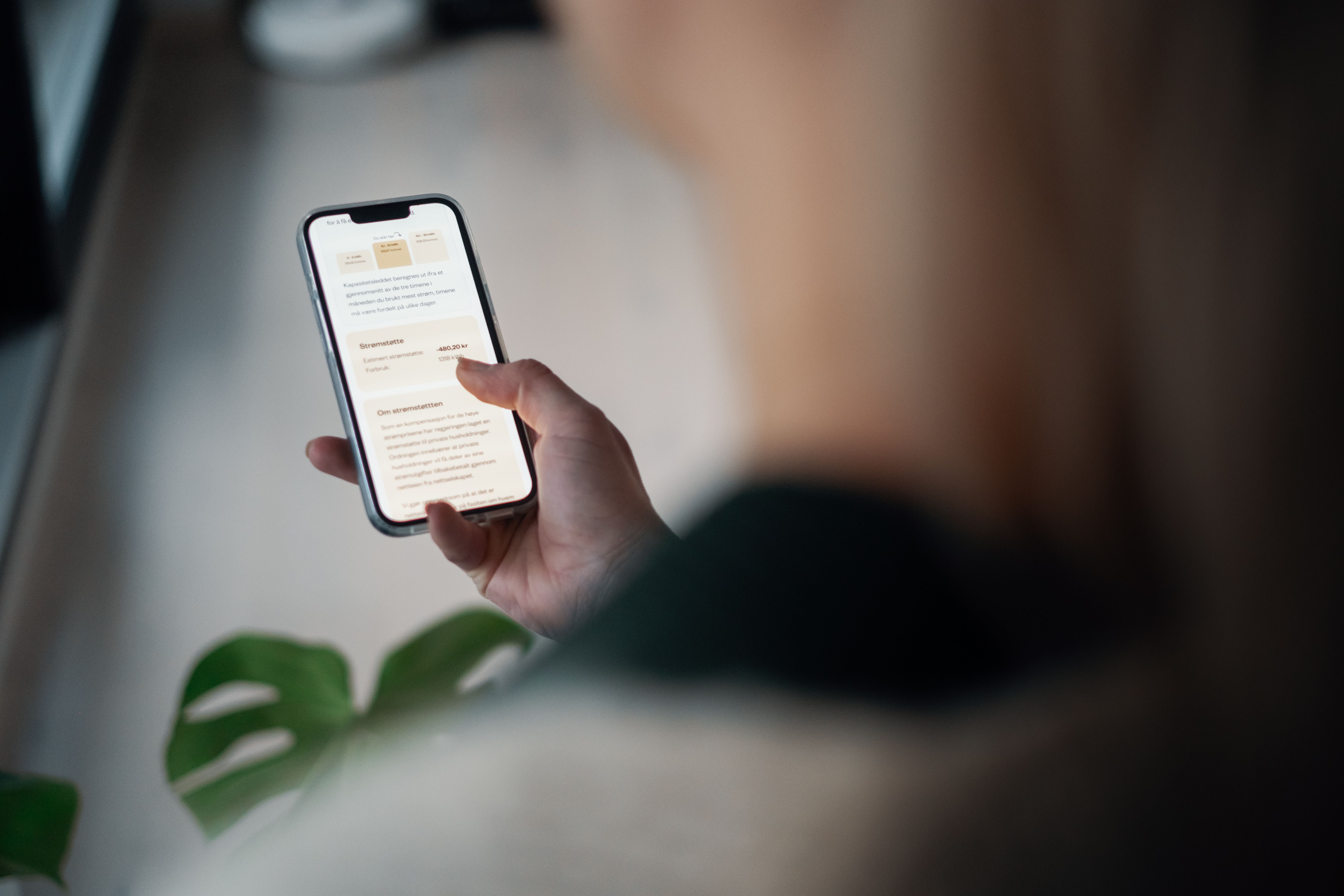 Person som leser om strømstøtte på sin mobiltelefon