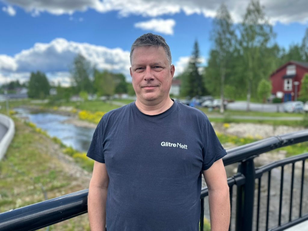 Mann smiler foran en elv på en bru