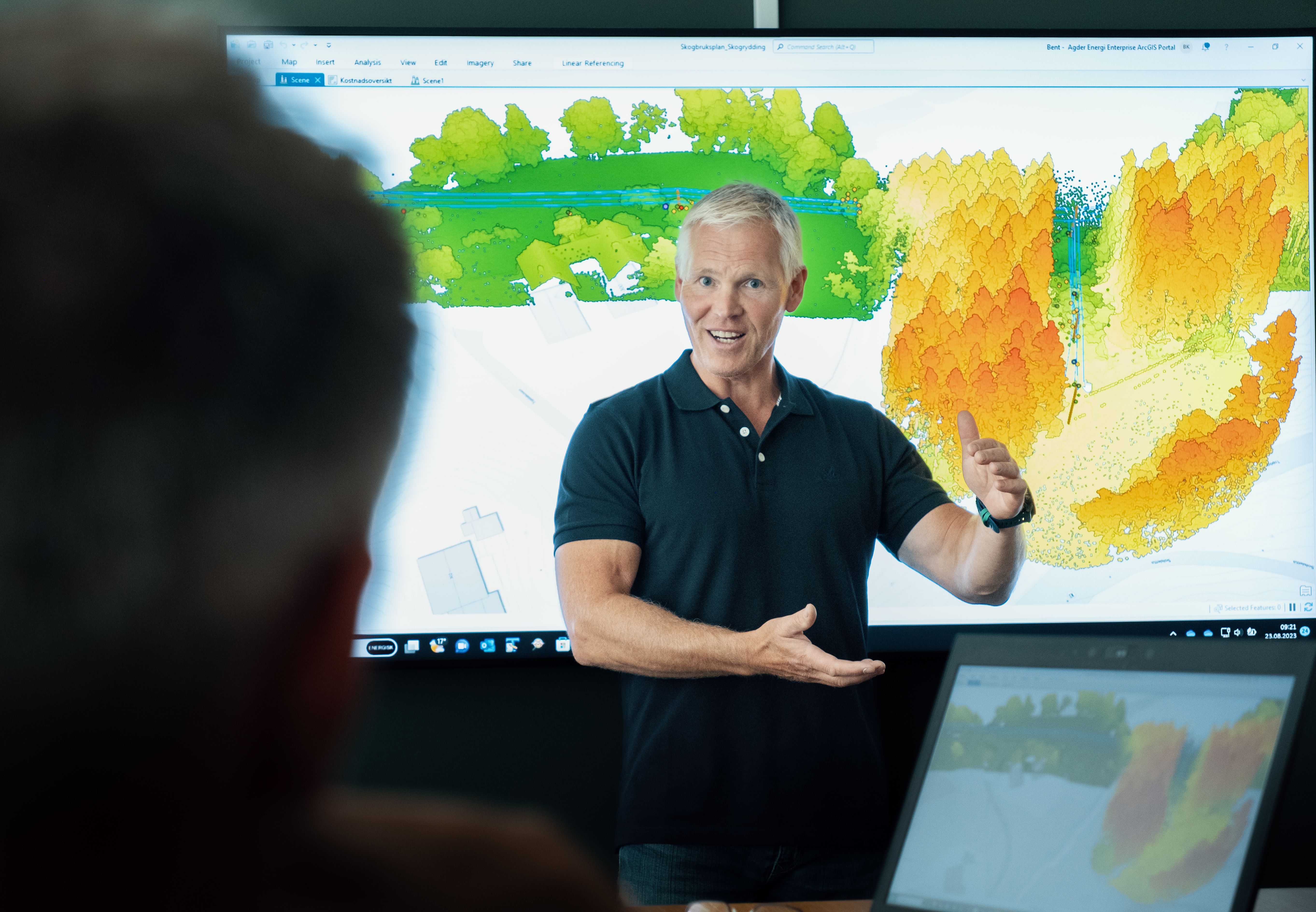 Mann foran skjerm, viser frem et kart til et publikum.