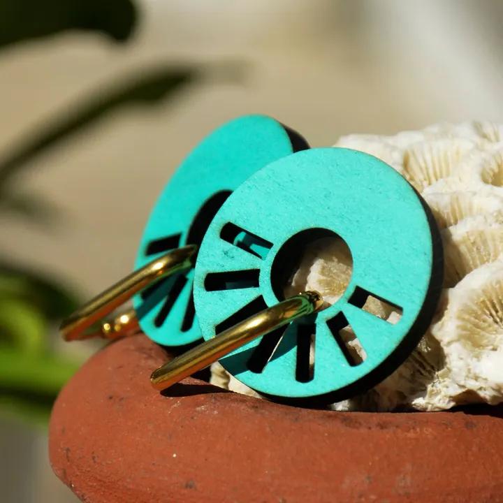 Pendentifs ronds ajourés, turquoise, sur des anneaux dorés, posés sur un pot en terre cuite