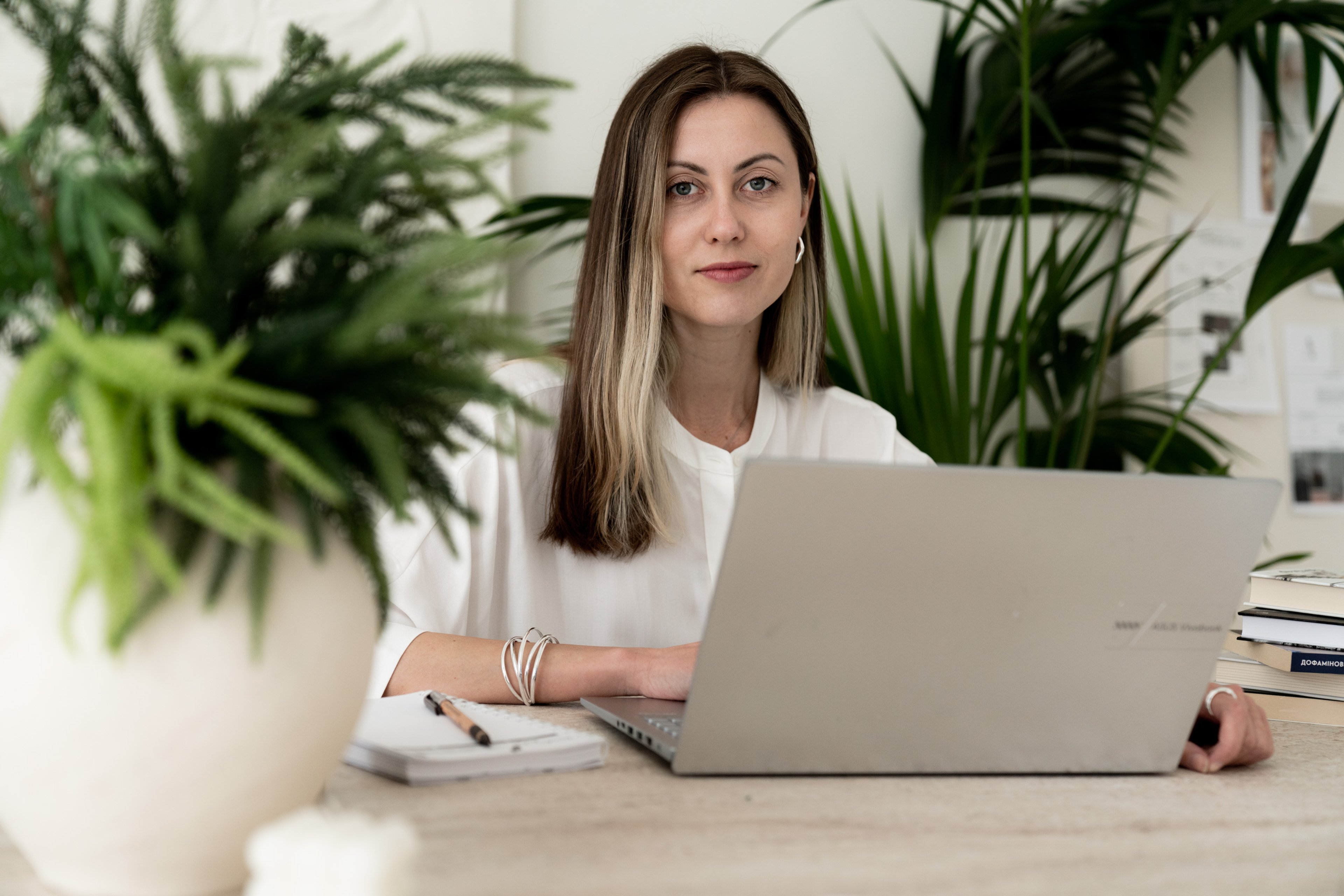Psychologist at her desk with a laptop, surrounded by plants