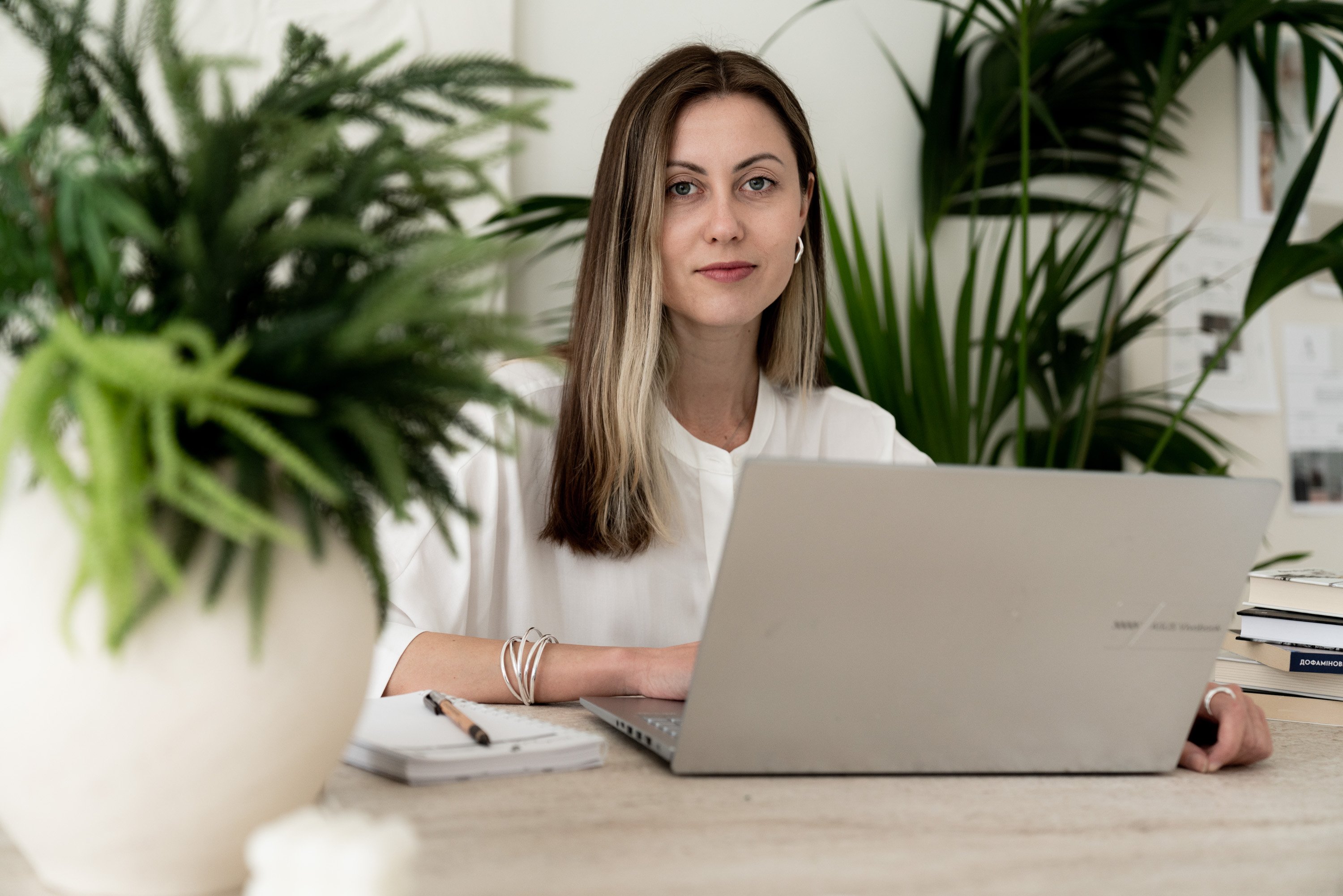 Psychologist at her desk with a laptop, surrounded by plants