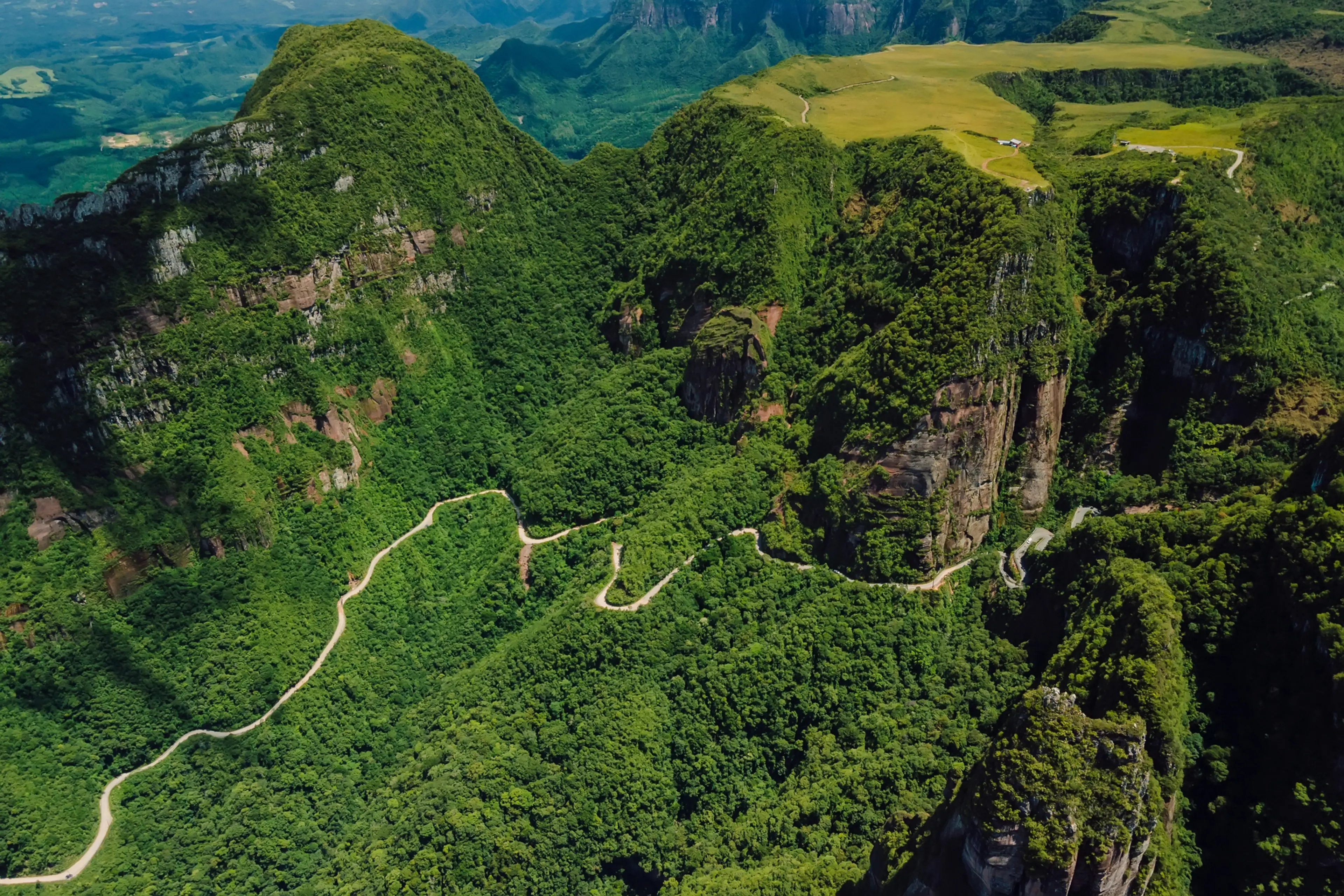 Aerial view of a winding road through lush green mountains.