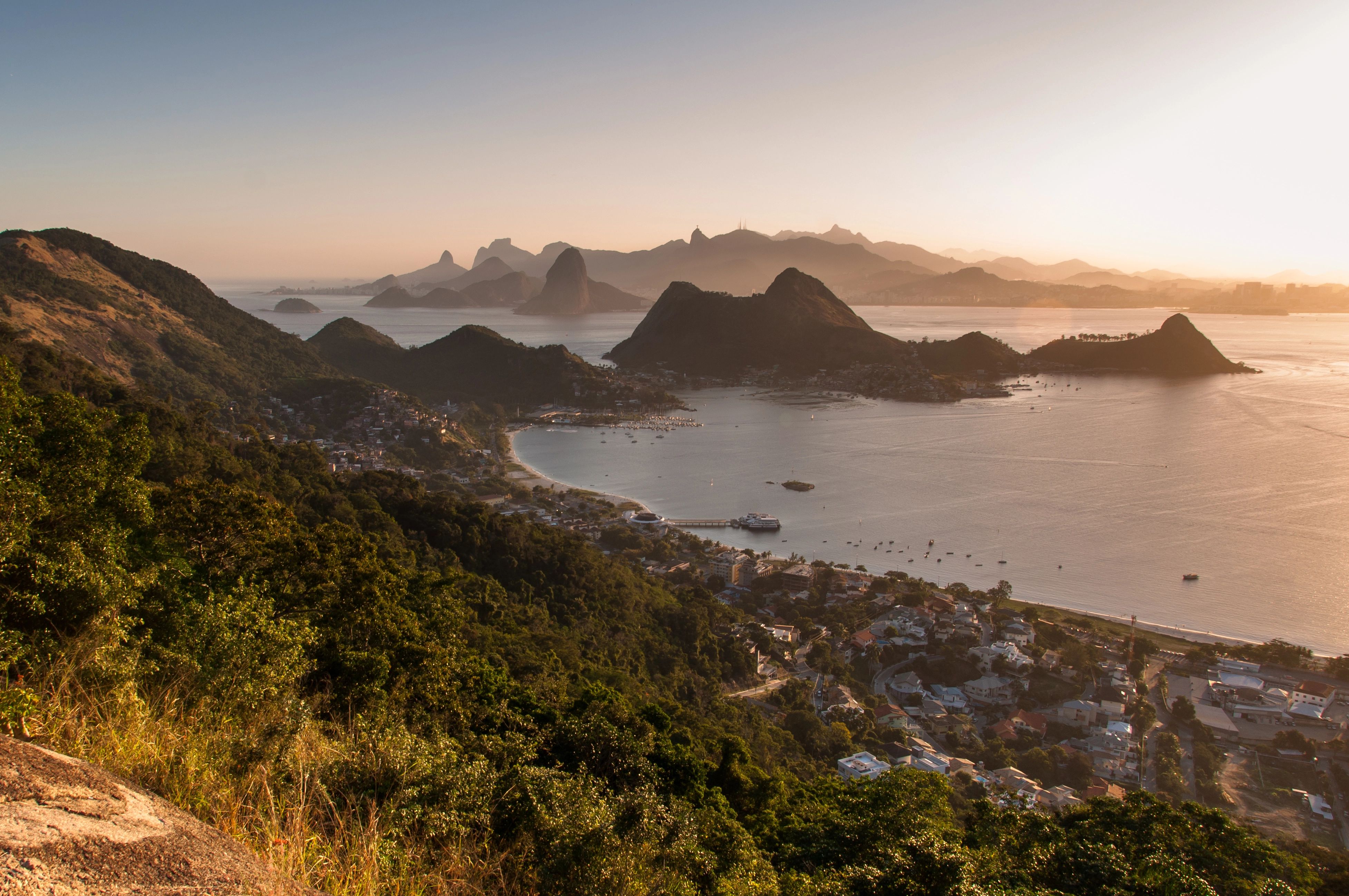Panoramic view of Rio de Janeiro's bay, mountains, and city at sunset.