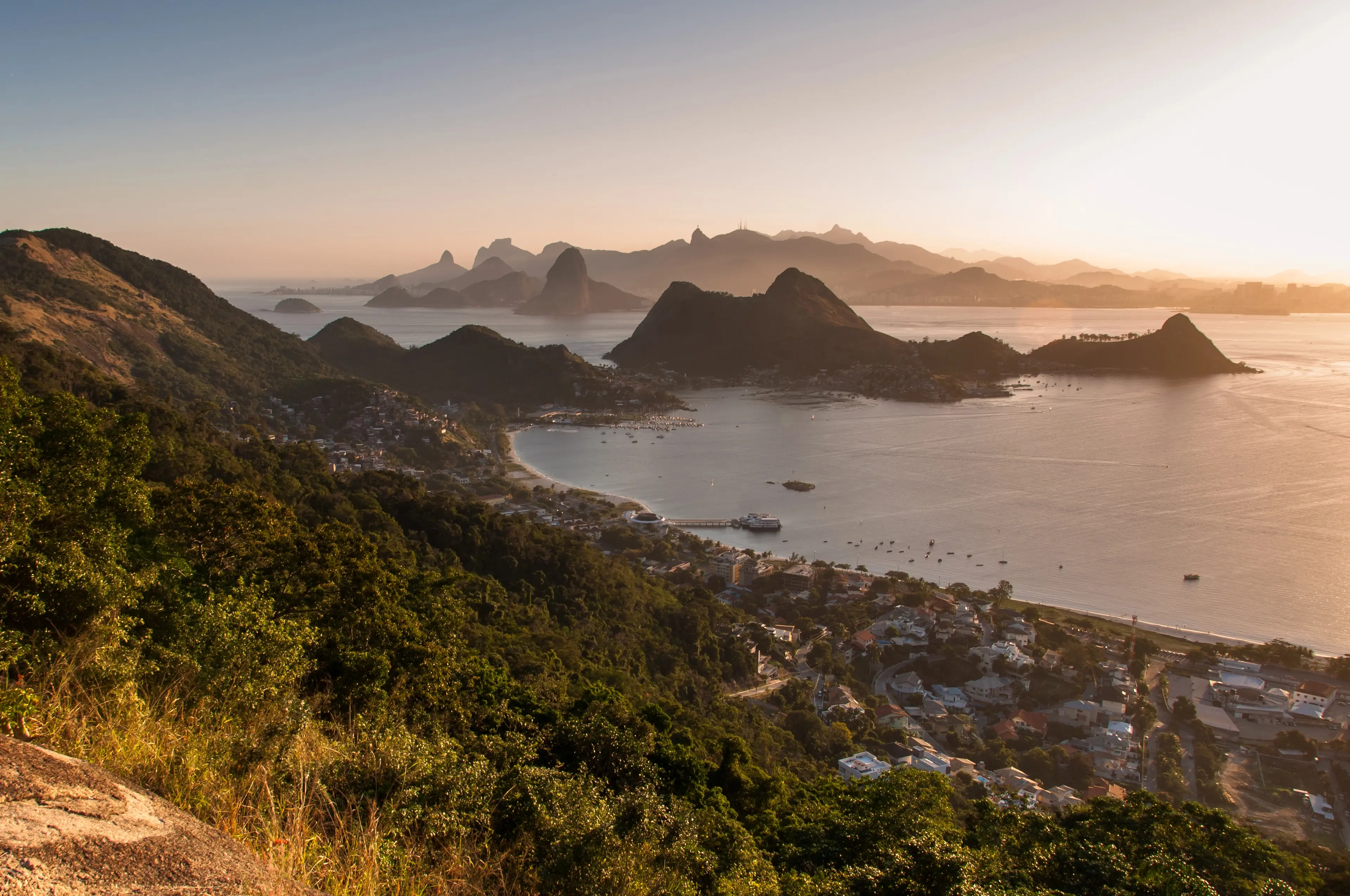 Panoramic view of Rio de Janeiro's bay, mountains, and city at sunset.