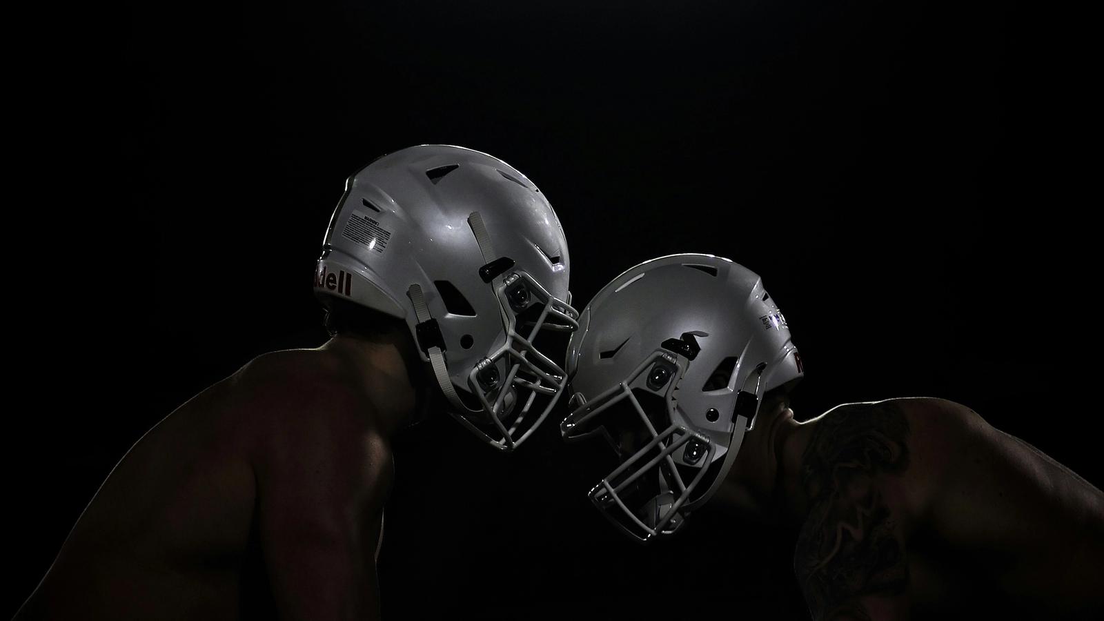 Two football players clash under floodlights
