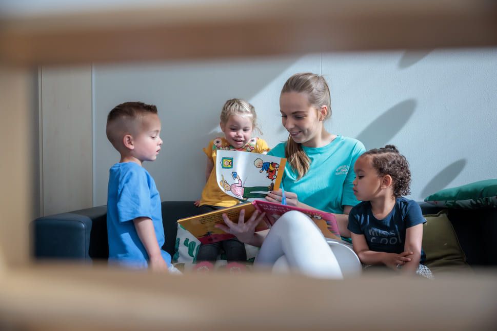 kinderen lezen boekje met leidster