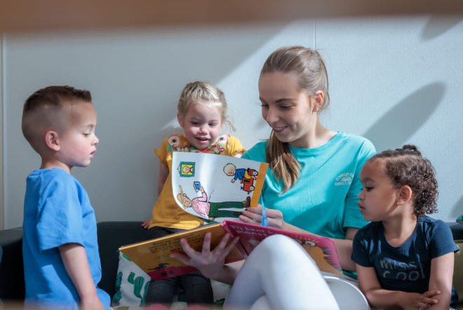 kinderen lezen boekje met leidster