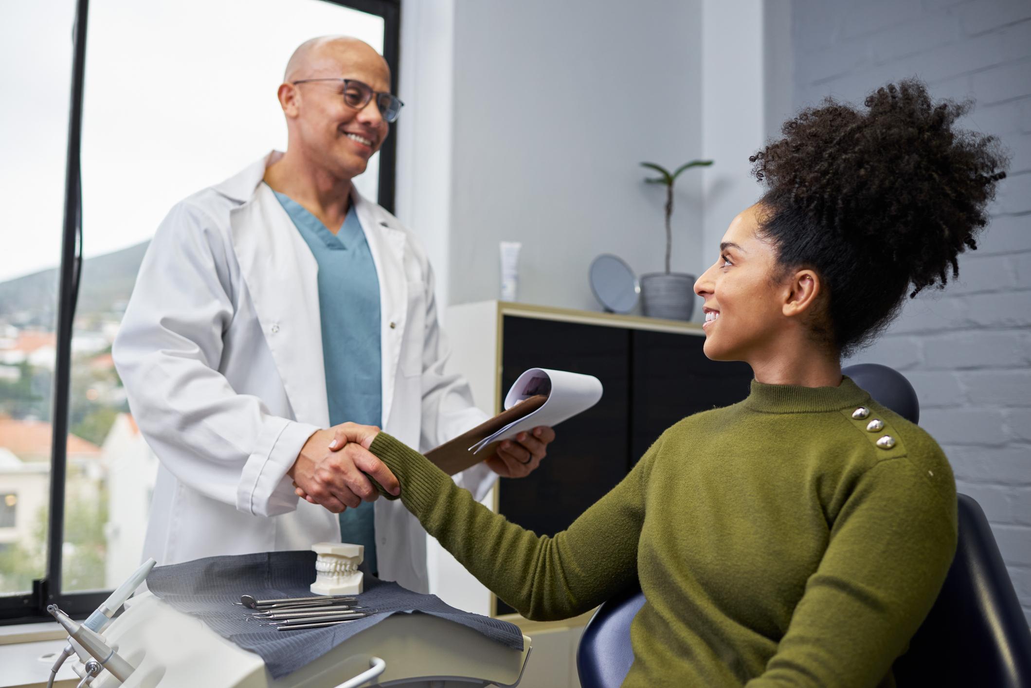 A cheerful dentist engages in a professional consultation with a female patient in a bright dental clinic. The image captures trust and professionalism, showcasing modern medical care and positive patient experiences.