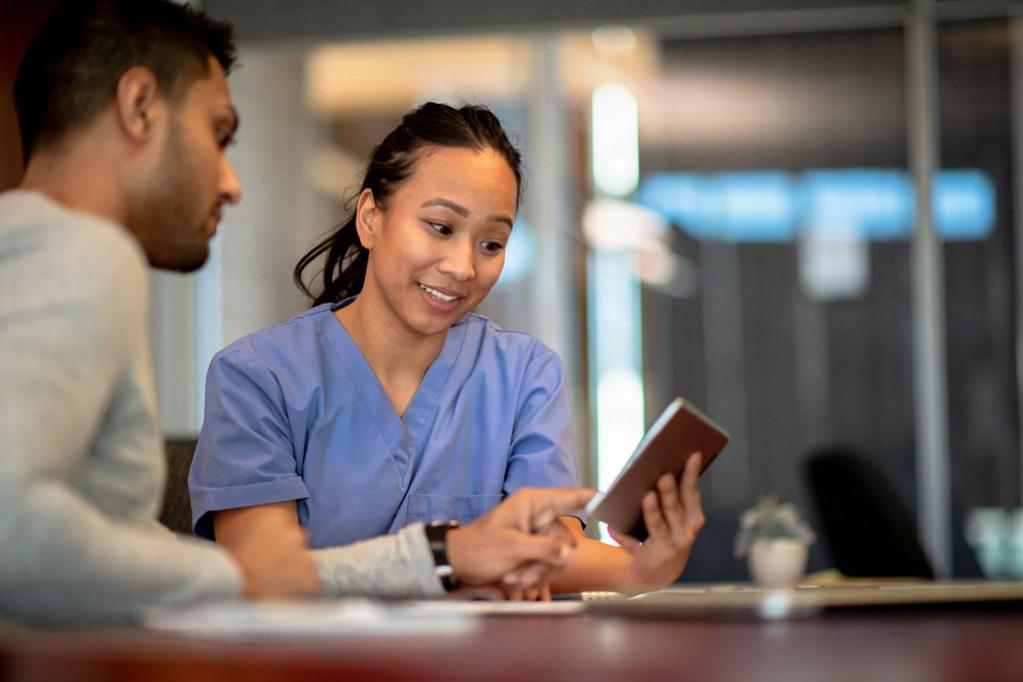 Healthcare professional showing information on a tablet to a patient.