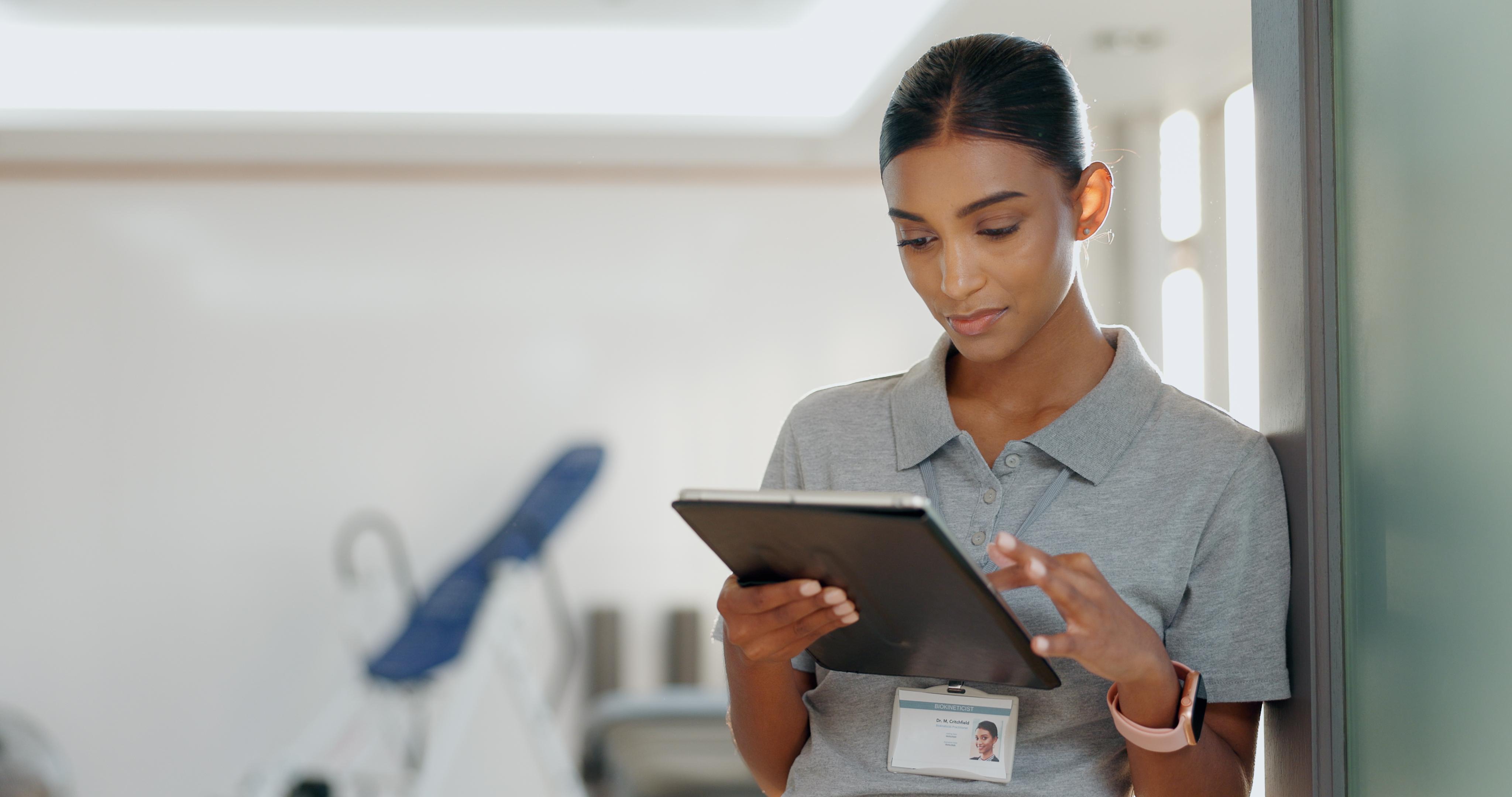 Dental staff member using a tablet in a clinical office setting.