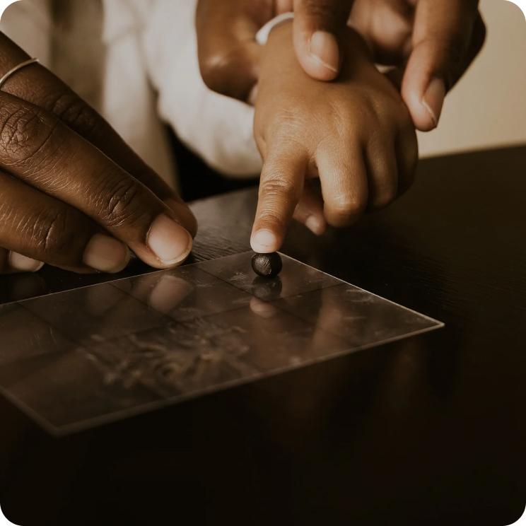 A child's fingertip pressing into a bead of wax