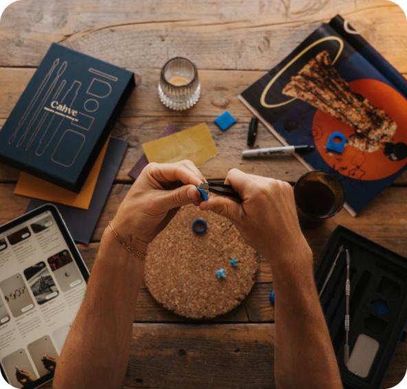 Hands carving blue wax at a wooden table