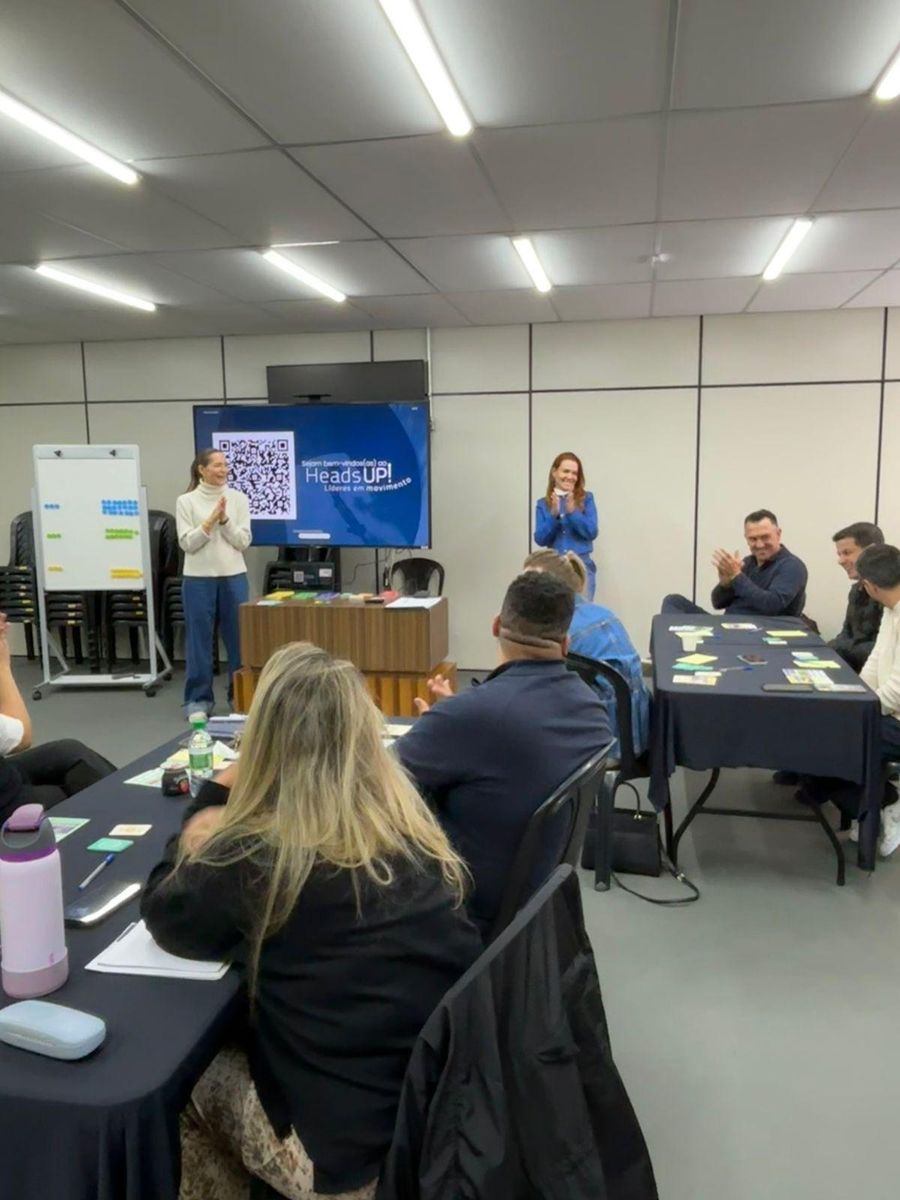 Andrea Eboli conduzindo um workshop com participantes em mesas de trabalho