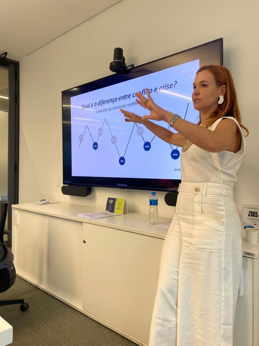 Andrea Eboli conduzindo uma sessão; o slide pergunta qual é a diferença entre conflito e crise