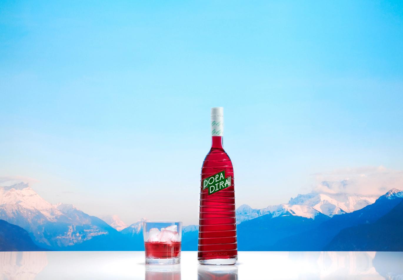 Rocks glass with Doladira poured in, Doladira bottle, in front of a snowy mountain range